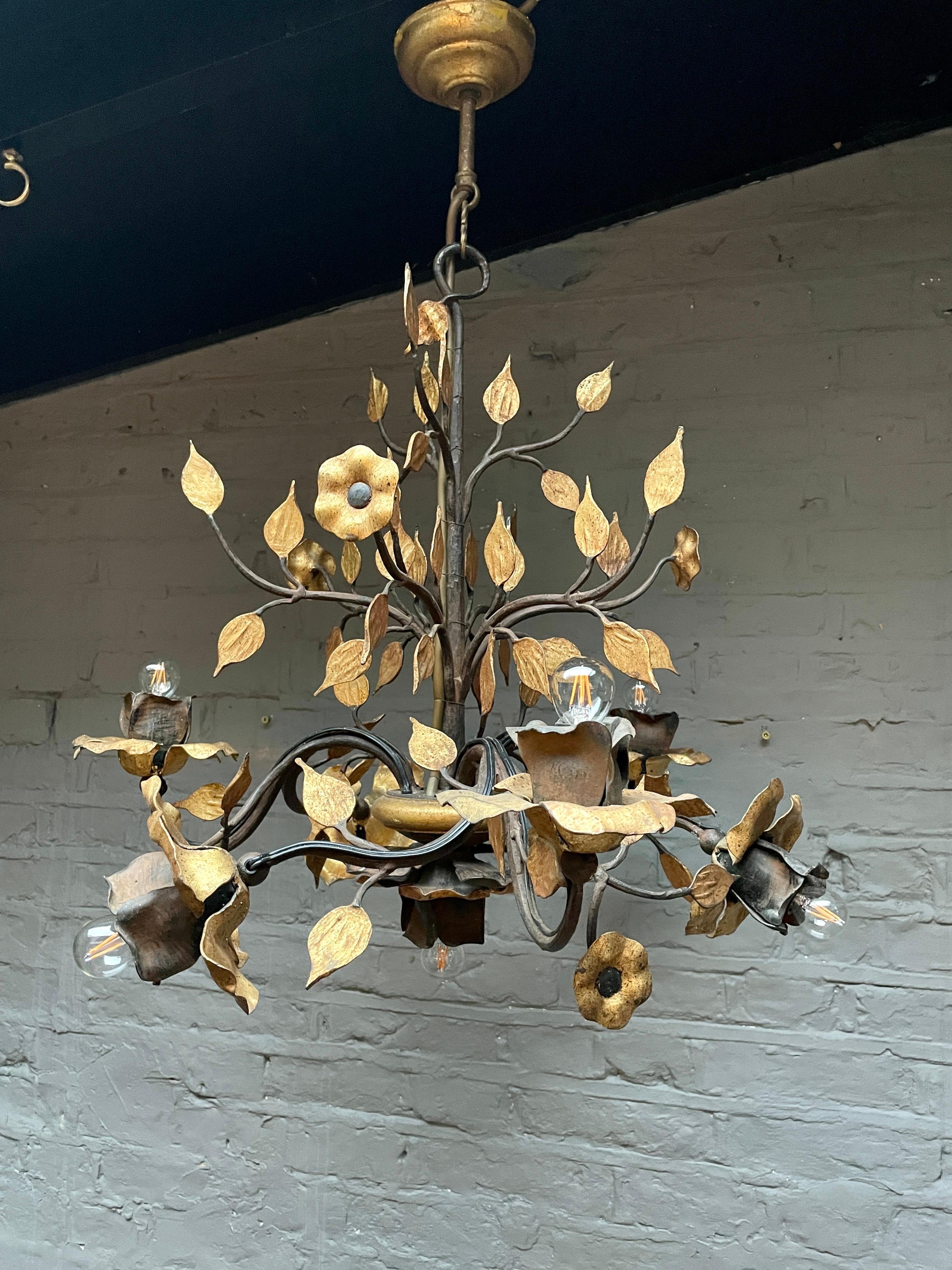 A wrought iron chandelier in black finish with gold gilt accents in an organic, floral and foliate design. Very well executed, finished with delicate gilding and details. The chandelier has 6 branches decorated with foliage and flowers, the bulb