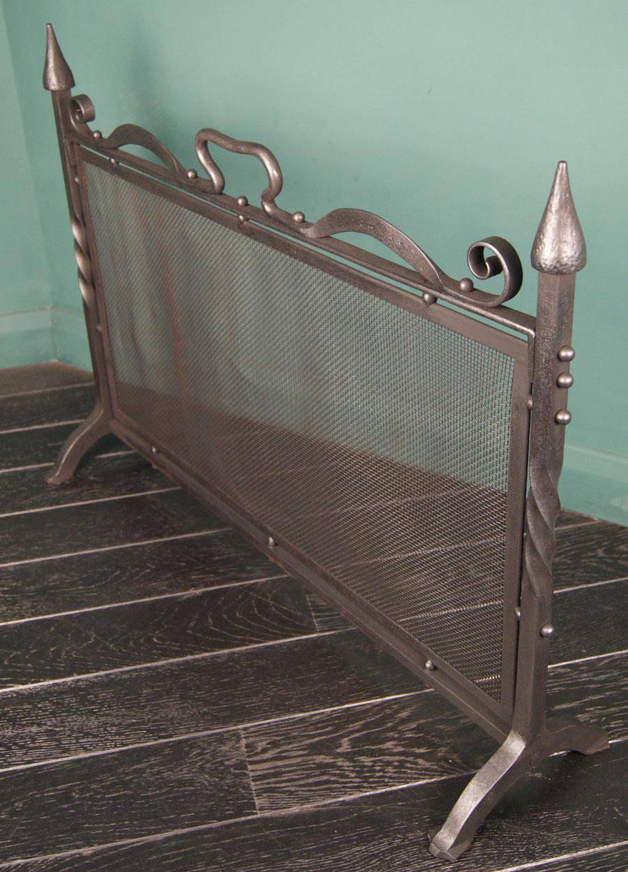 A wrought-iron fire screen. The uprights sit on arched feet with central twist detail and pinnacle finials uppermost. The fire mesh is housed in an inner frame under a wrought scrolled handle. Restored.
Circa 1900