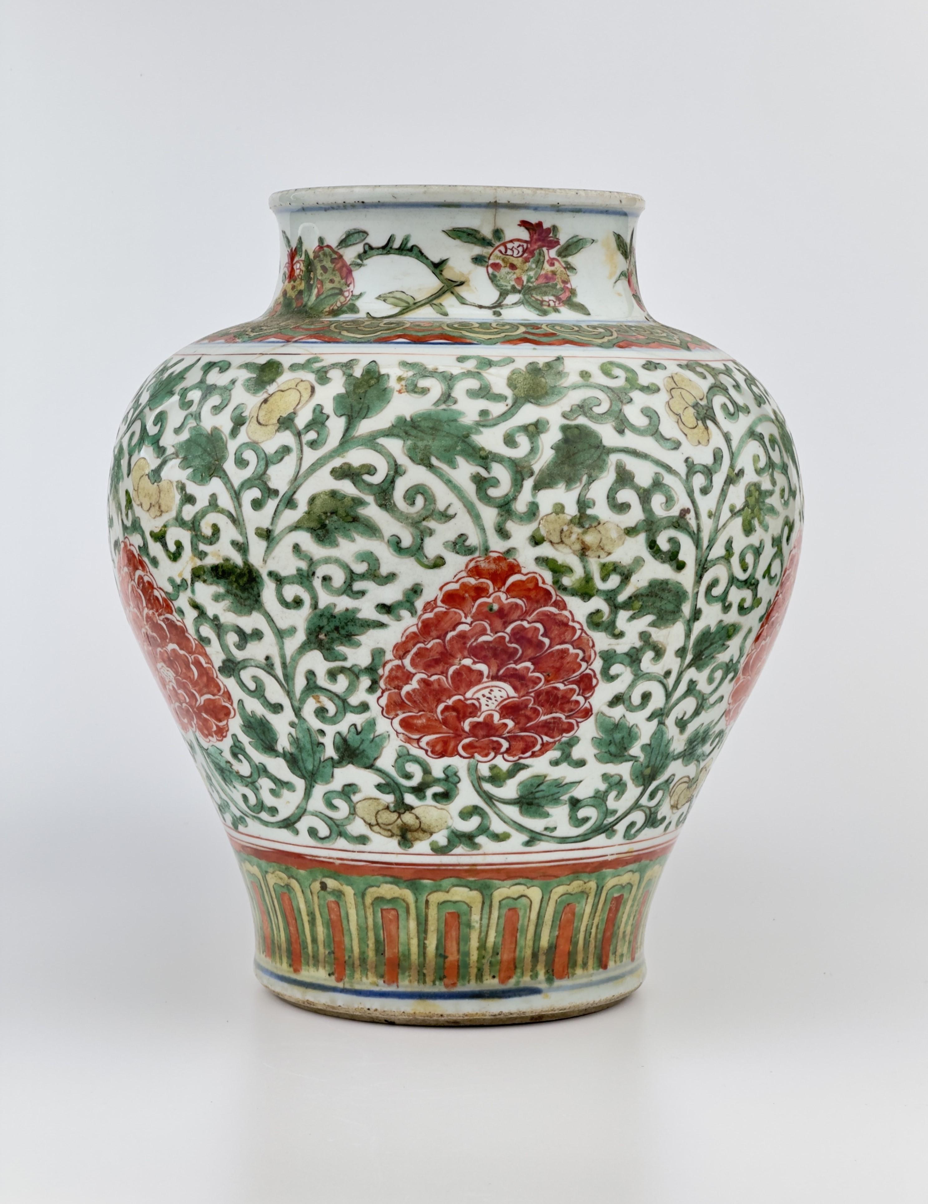 The jar features a balanced and robust form, typical of the Transitional period, which was a time of significant change and innovation in Chinese porcelain art. The decoration is exuberant, with bold red and green colors dominating the palette,