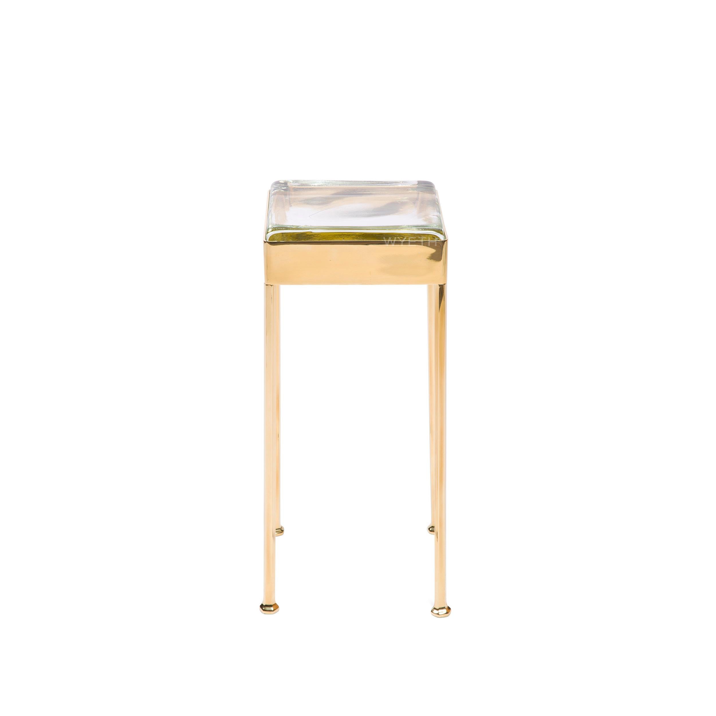 A bronze studio-made cocktail table, having a square banded apron holding a glass tile that rests on four faceted legs. Available in polished, brushed, patinated and blackened bronze. Made by the Wyeth Workshop, NY.