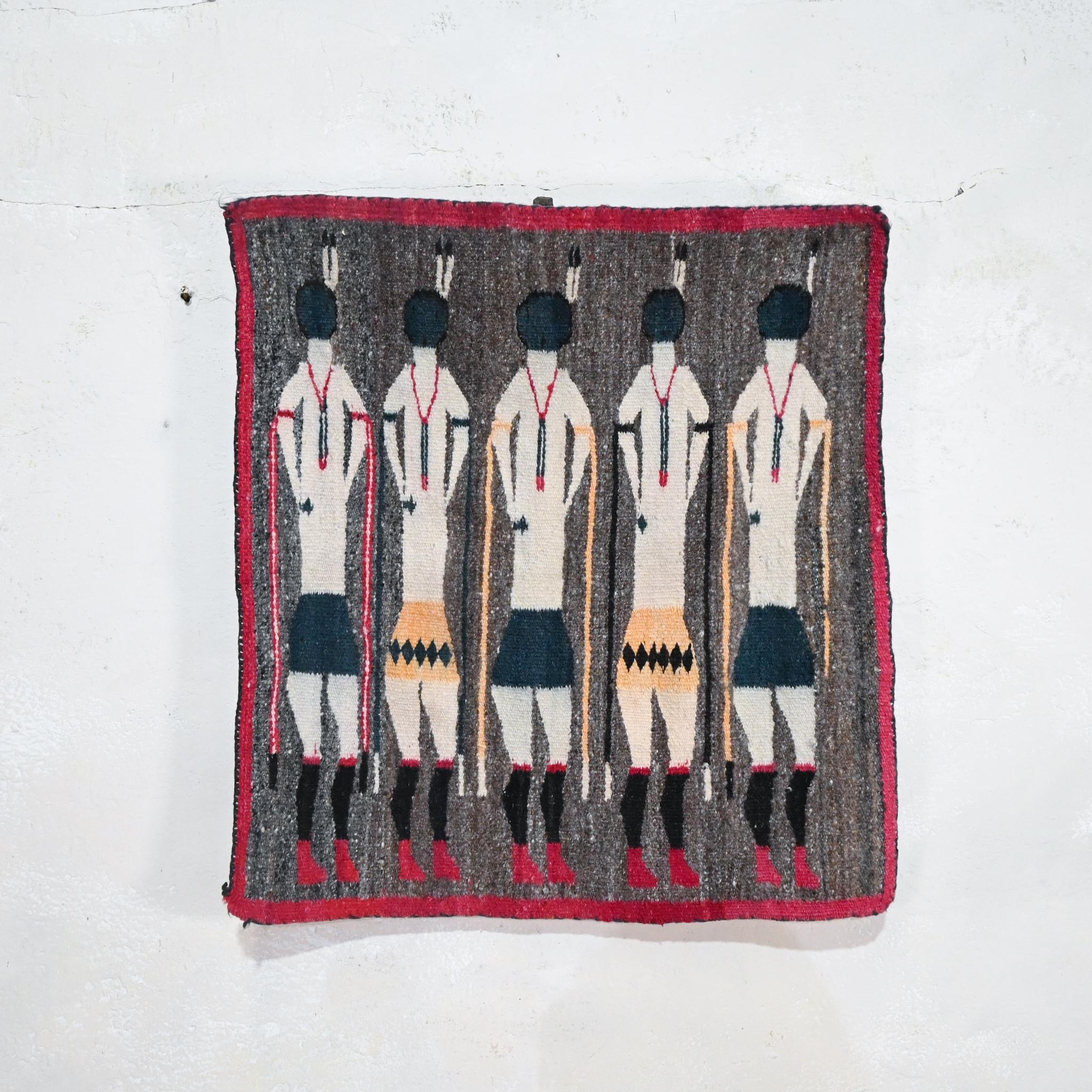A Yei Navajo Figural double-sided flat woven wall hanging - circa 1930. Displaying five standing figures on an deep speckled grey ground, framed by a red border. 
 
The Yei iconography is related to Navajo religious sandpaintings. Navajo religion