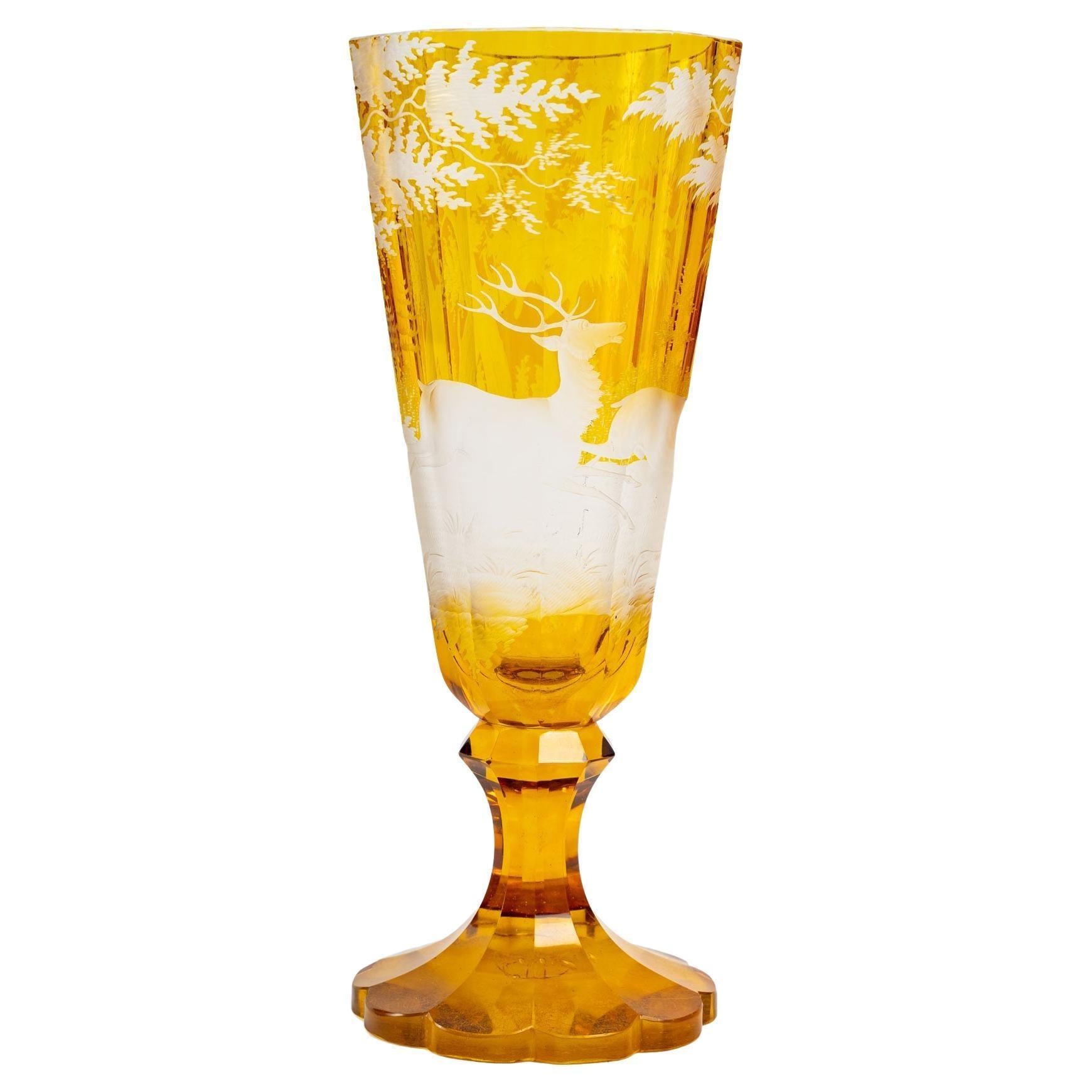 A yellow Bohemian crystal goblet on a foot engraved with a hunting scene, 19th century, Napoleon III period.
Measures: H: 22 cm, d: 8,5 cm.
 