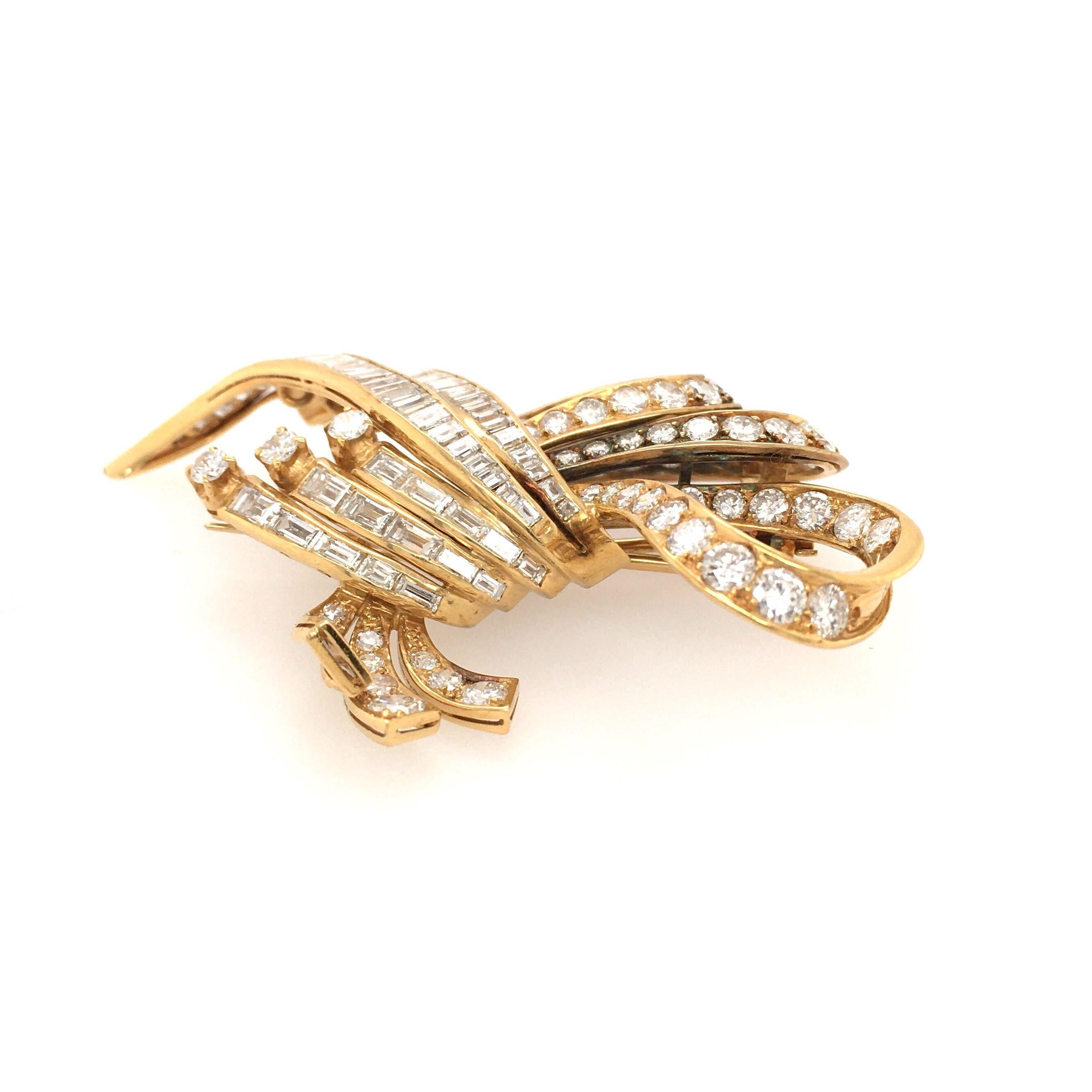 An 18 karat yellow gold and diamond brooch. Designed as a scrolling circular and baguette cut diamond ribbon. Sixty one (61) circular and fifty five (55) baguette cut diamonds weigh approximately 5.20 carats. Length is approximately 2 1/2 inches,