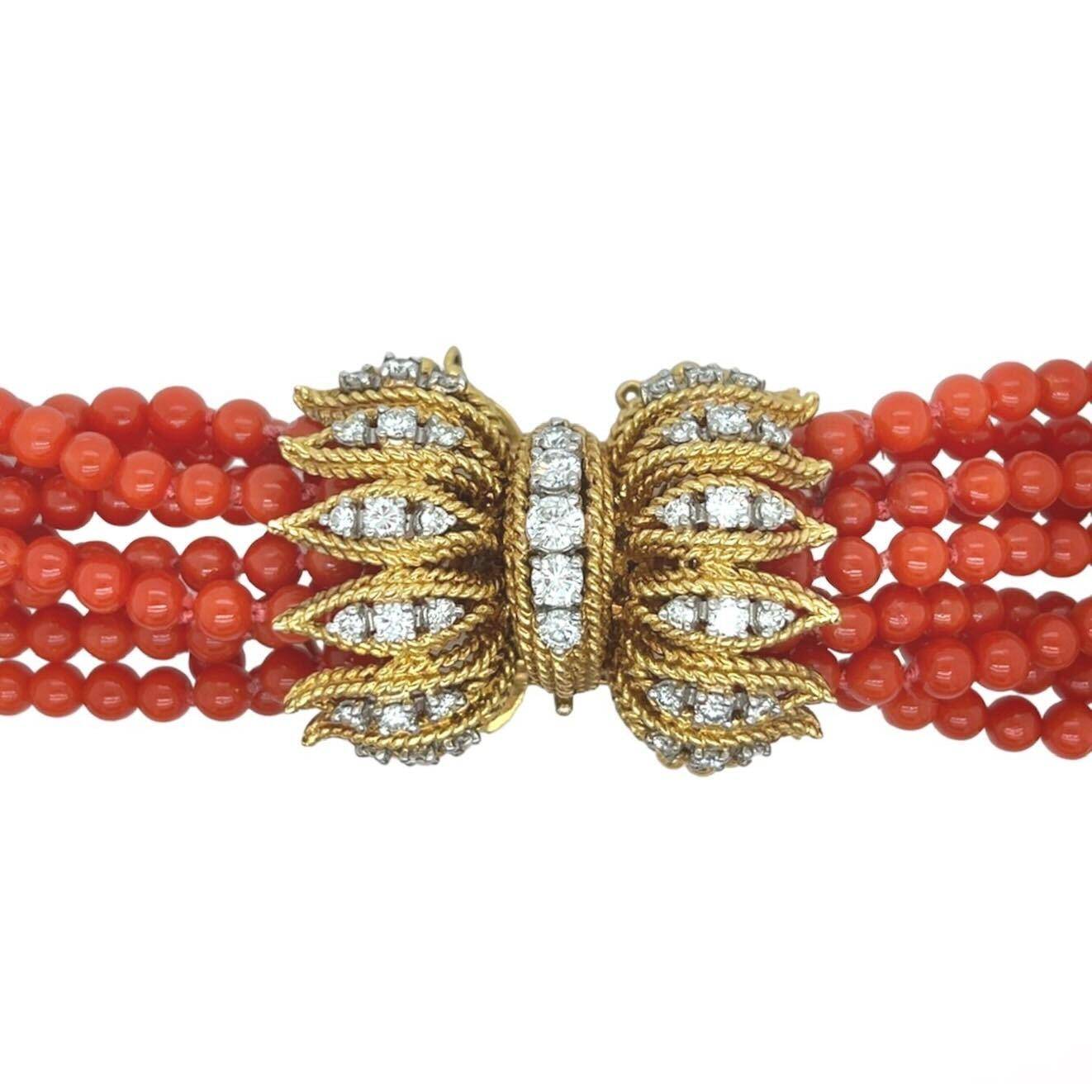 An 18 karat yellow gold, coral and diamond necklace.  Designed as nine (9) strands graduated in length of deep orange coral beads measuring approximately 3.9 mm completed by a double sided clasp set with approximately forty one (41) round brilliant