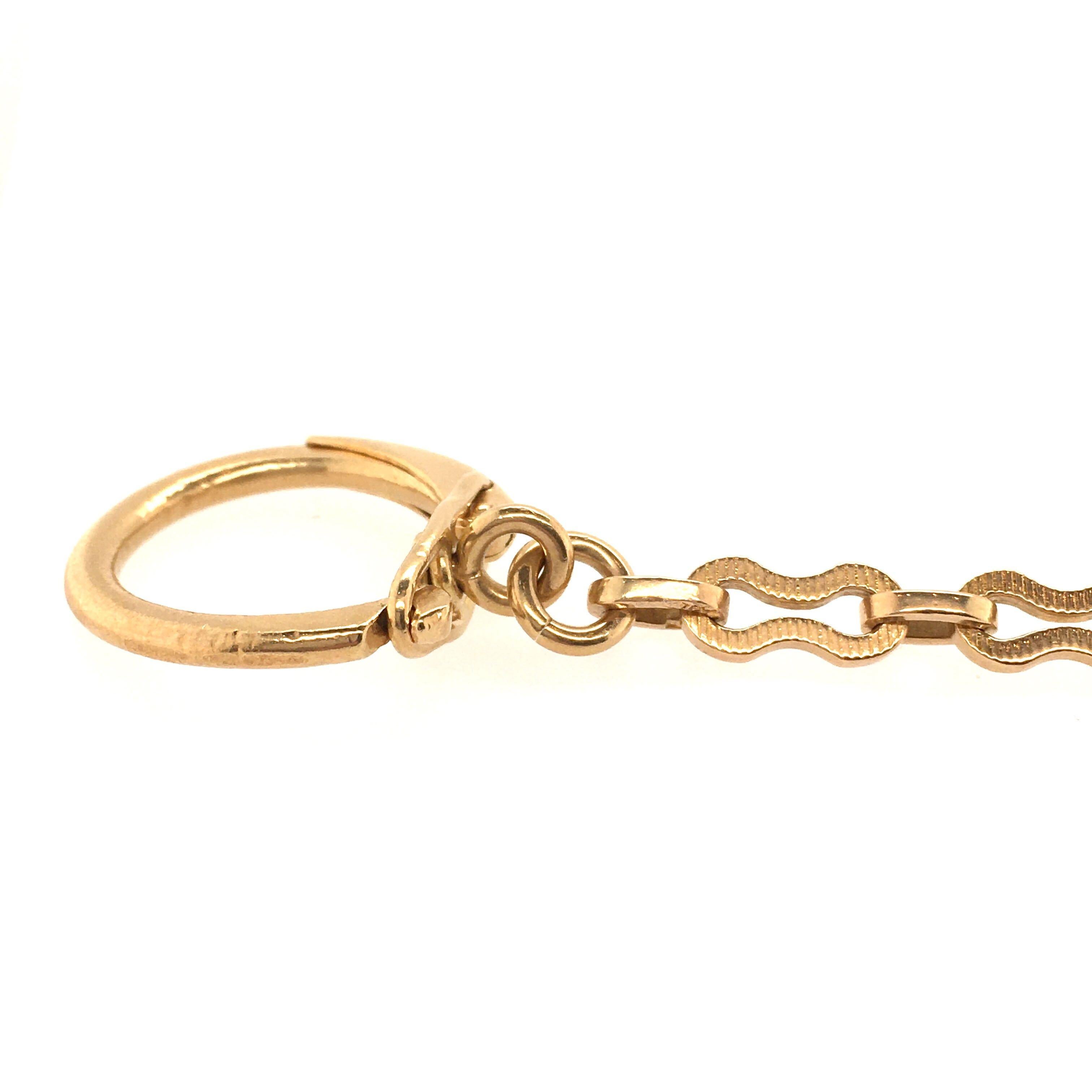 An 18 and 14 karat yellow gold key chain. Suspending a disc depicting The Mouth of Truth, from a fancy link chain. Diameter of disc is approximately 1 inch, length is approximately 4 1/2 inches, gross weight is approximately 21.8 grams. 