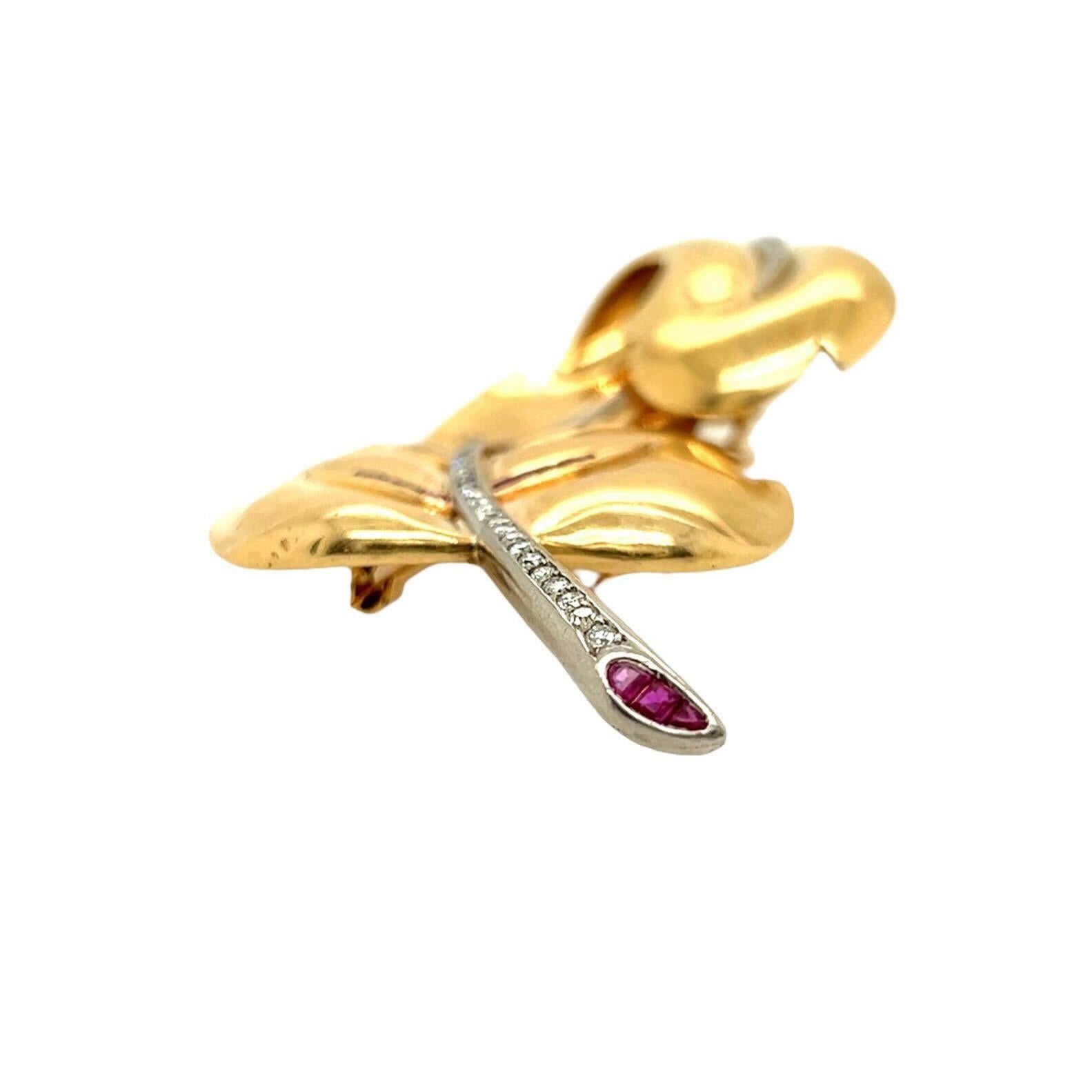 A 14 karat yellow gold, ruby and diamond brooch, circa 1940s.  Fashioned as a curling leaf, its main vein formed of approximately thirty nine (39) round brilliant cut diamonds and the stem end and subsidiary veins formed of approximately thirty (30)