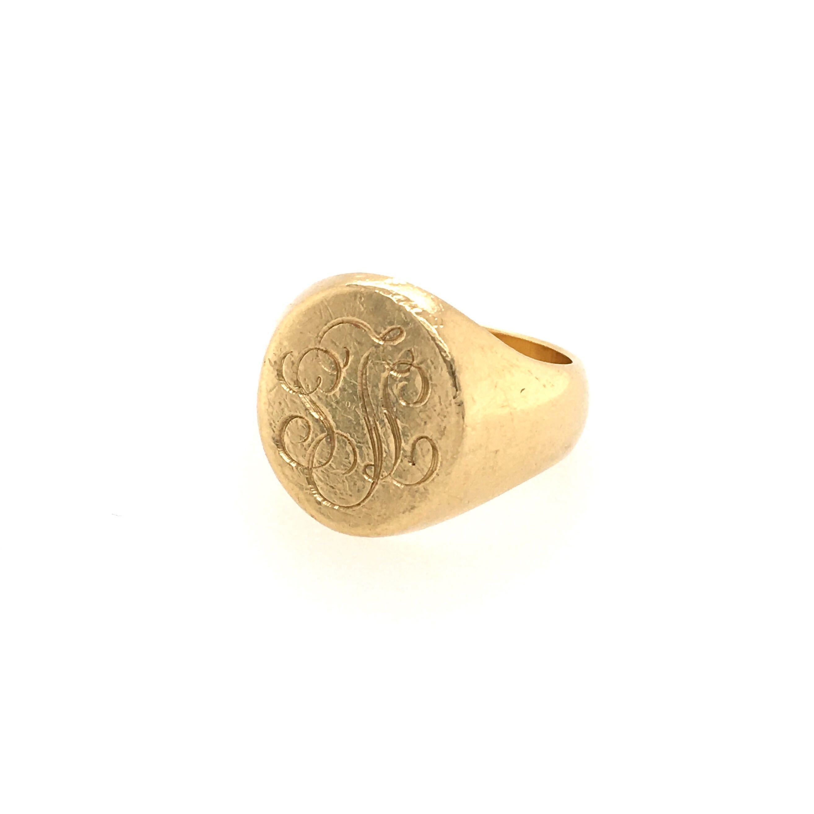 An 18 karat yellow gold signet ring. The polished gold ring of oval outline, the top engraved with a script monogram. Size 7, gross weight is approximately 13.3 grams.