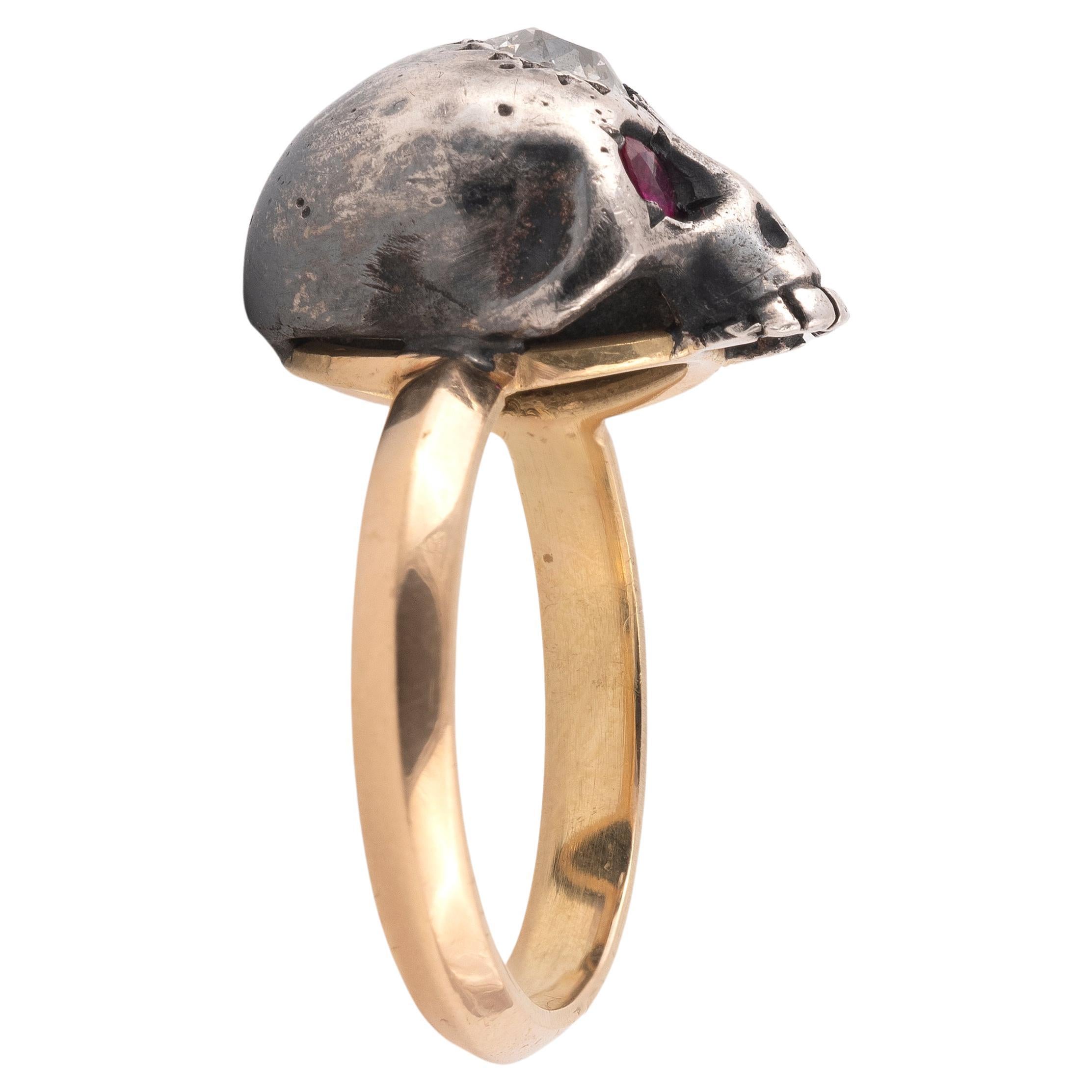 A yellow gold silver and diamond skull ring, the centre a skull with rubies eyes, split shoulders and plain designed shank, estimated total diamond weight 0.3carats, all in 18ct yellow gold.
Size 7
Weight: 6.33gr