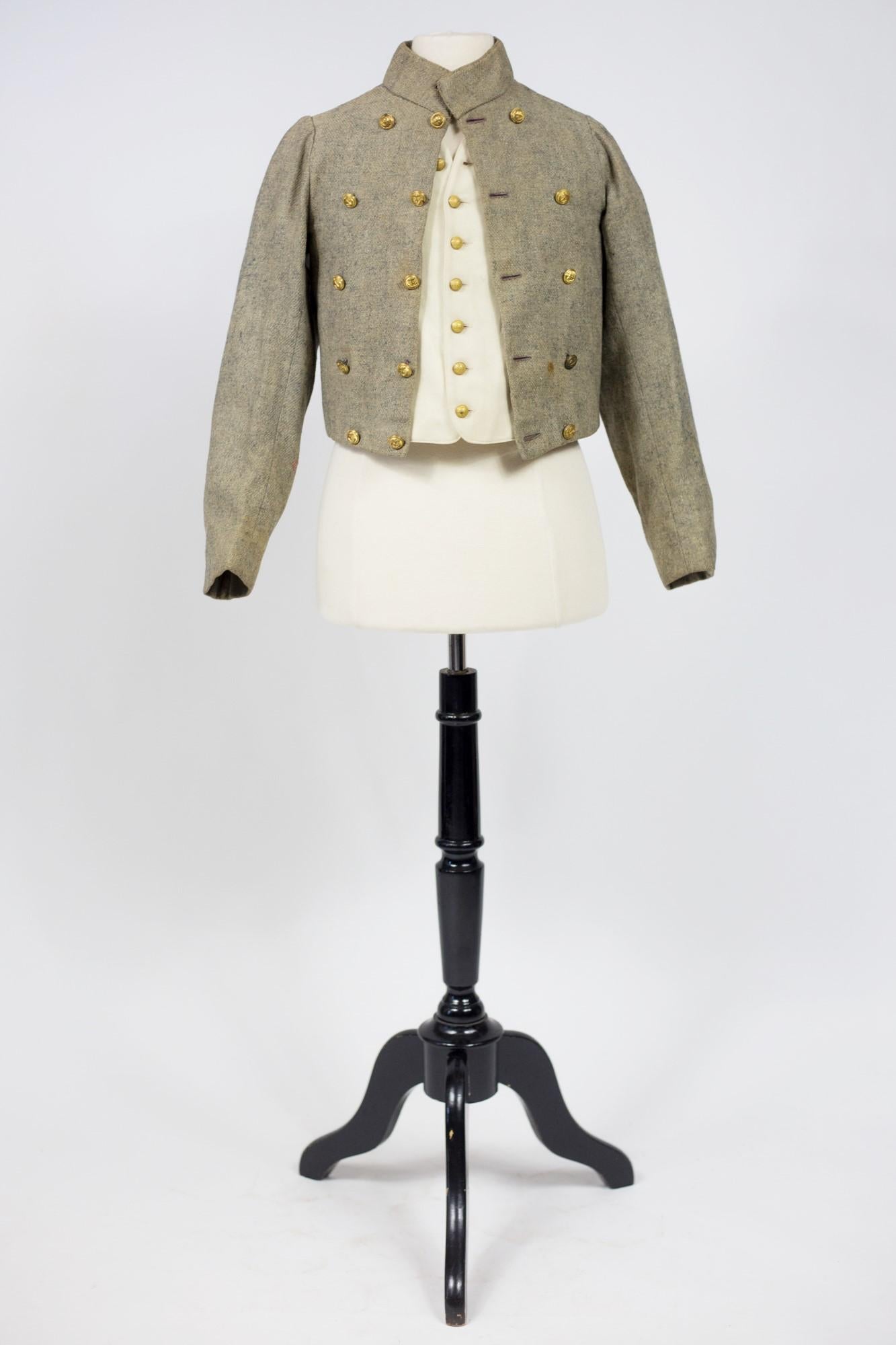Circa 1880-1900
France
A late 19th century petrol blue and cream mottled wool boy's suit and waistcoat. Small scooped out suit with tail, officer's collar, brass button cross fastening engraved with navy ink, brown cotton twill lining. A waistcoat