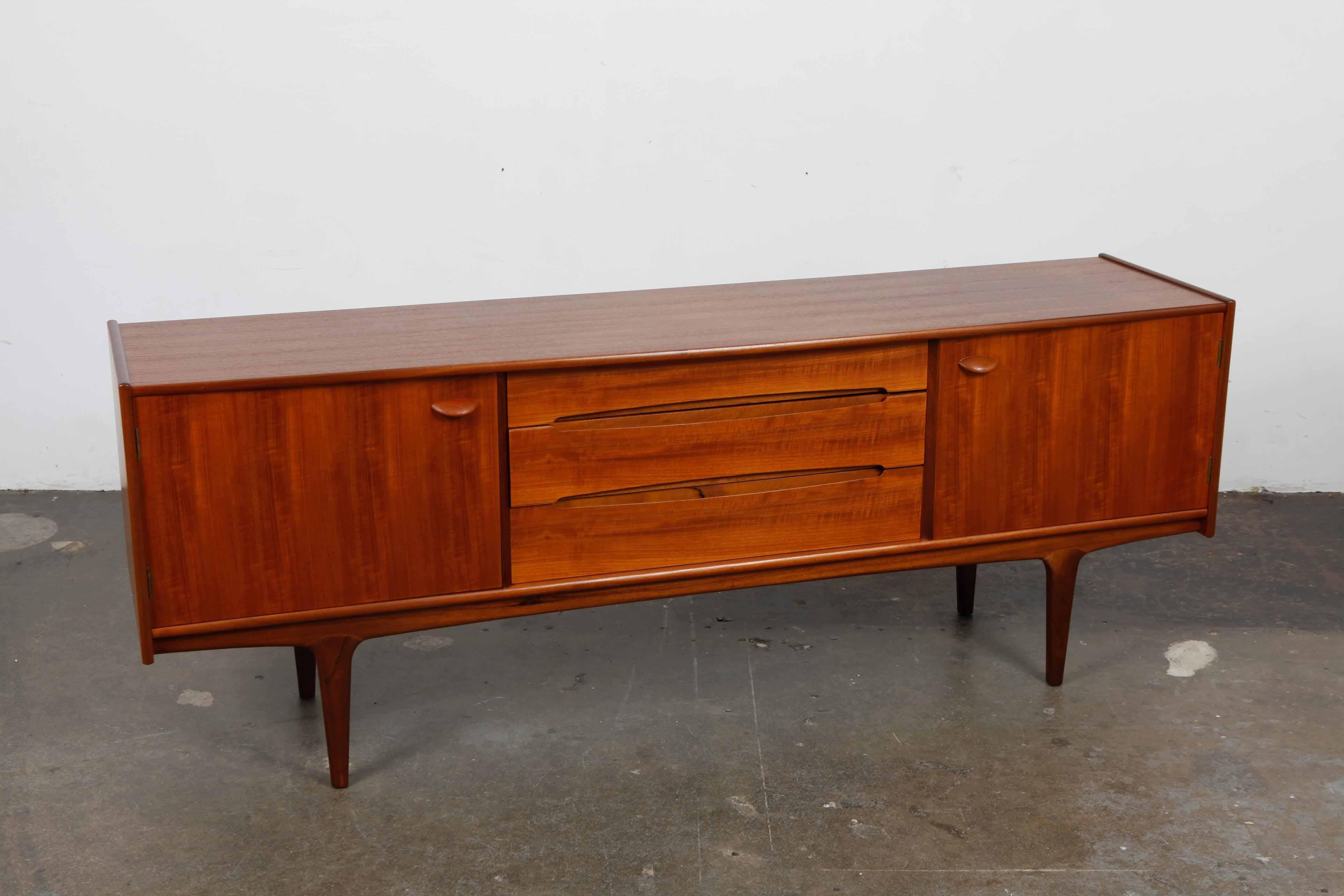 Beautiful low tola wood sideboard with arching curved drawer pulls and half disc door handles produced by A. Younger Ltd., England, 1950s. Newly refinished in satin lacquer.