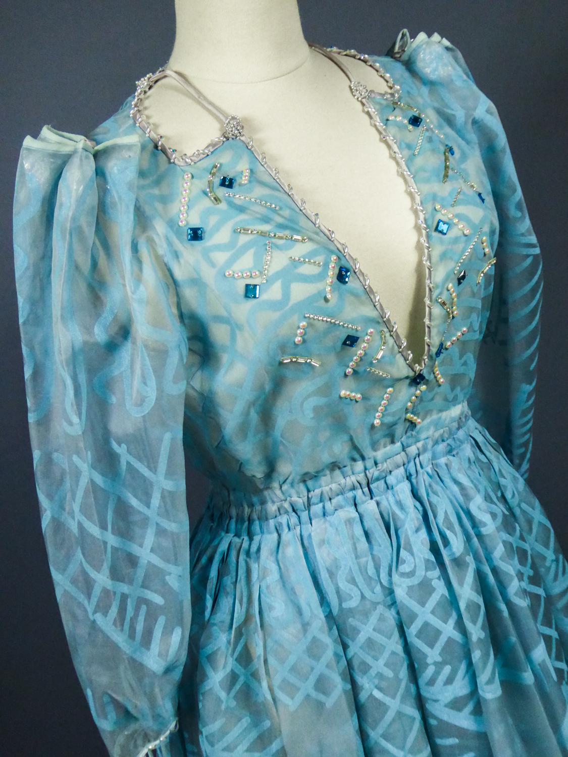 Circa 1980
Angleterre
Iconique longue robe de soirée de la célèbre designer anglaise Zandra Icone et datant des années 1980. Organza de soie translucide imprimé de motifs géométriques en zigzag de style ethnique et largement inspiré de la mode des