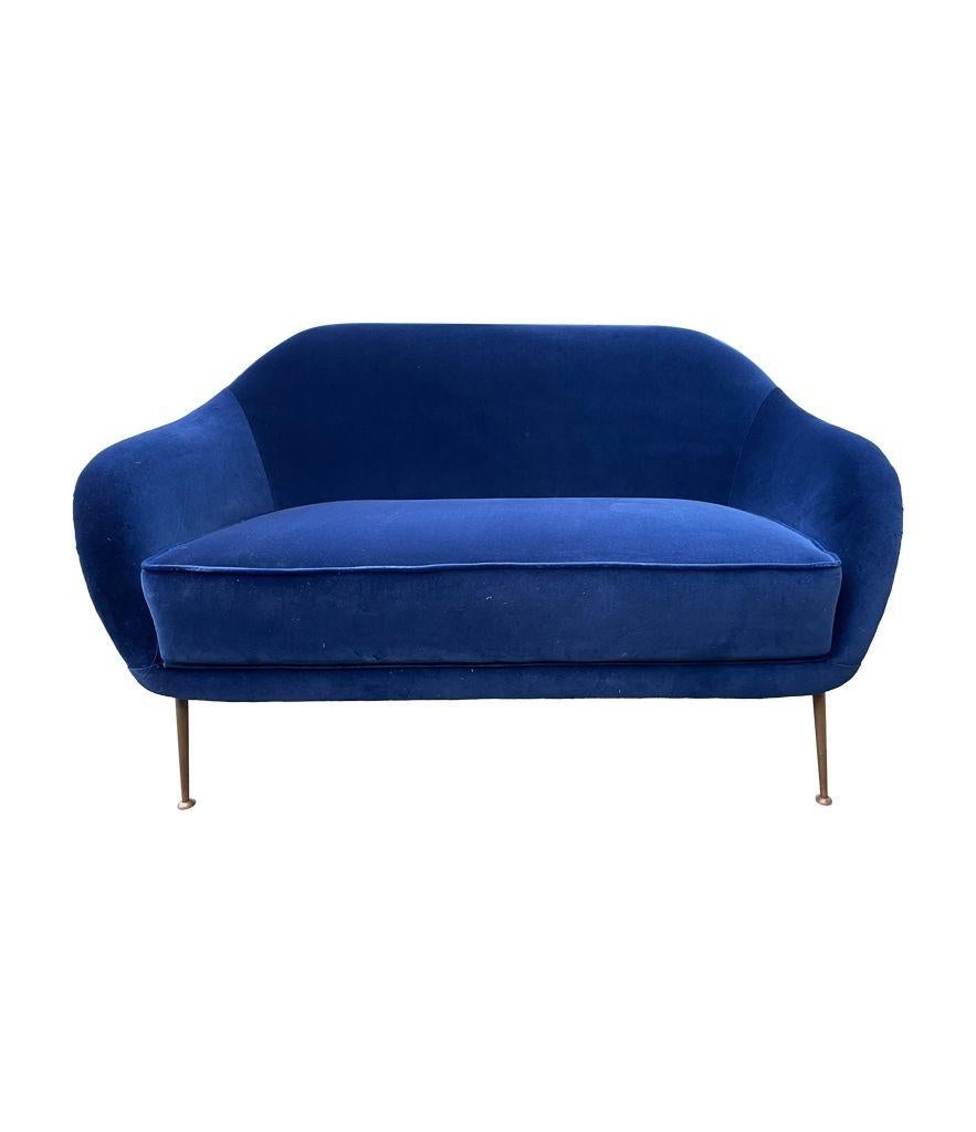A lovely 1950s Italian two seater. curved backed sofa with slender brass legs and newly upholstered in Designers Guild blue velvet.