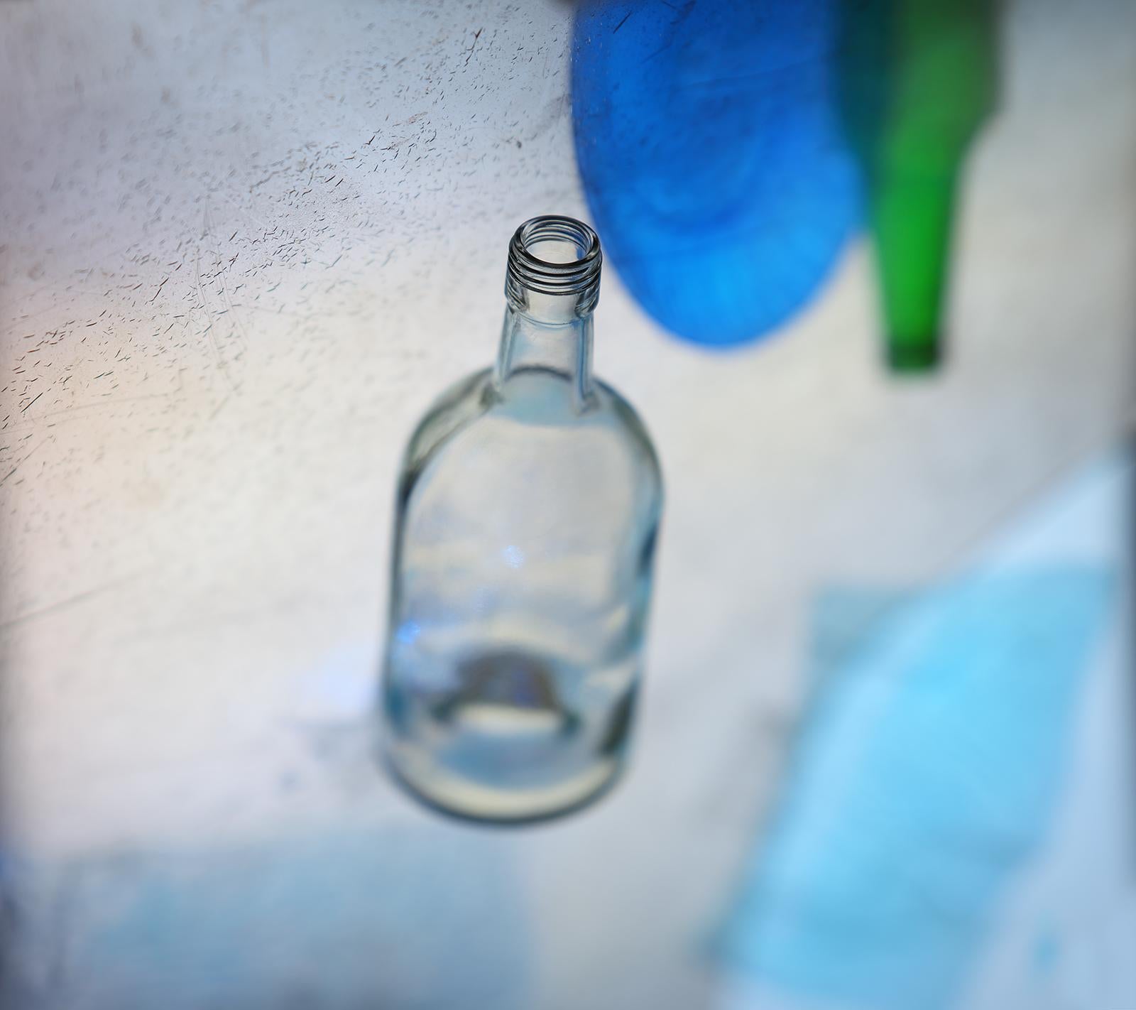 'Waterfront' by Vitalii Ledokollov -  is a powerful blue abstract figurative photography print. Bottles are used to create a subtle effect of figures. The artist brings life to ordinary subjects and reflects on relationships in the material world