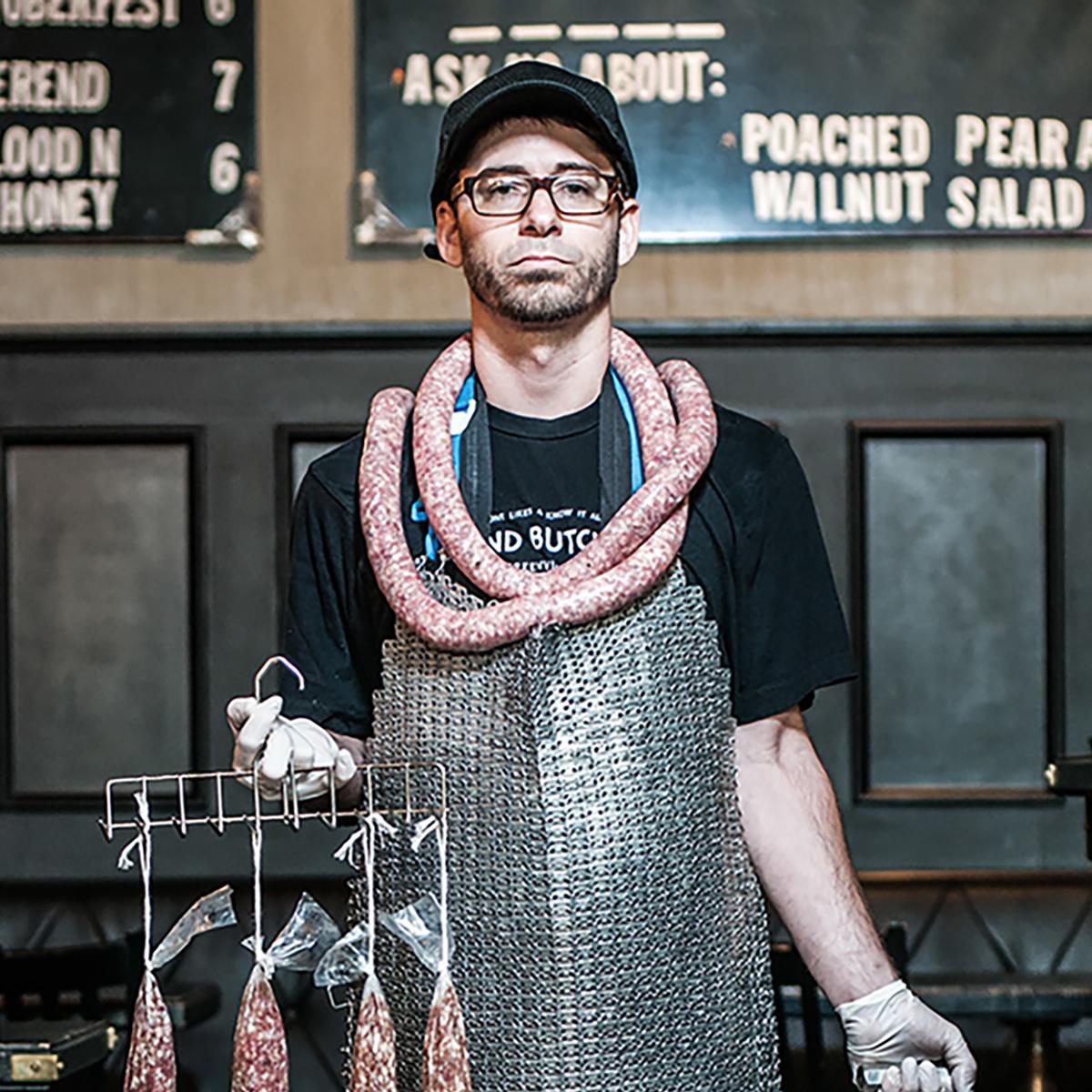 Butcher by Can Turkyilmaz. Photograph of butcher with sausages and pigs head For Sale 1