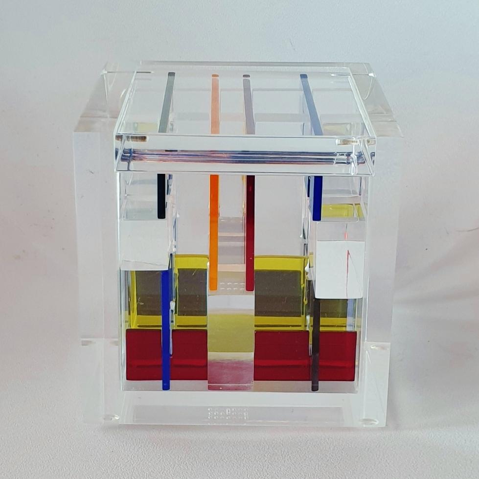 Homage to Mondriaan is a unique small size contemporary modern cube sculpture by the famous Dutch artist couple Nel Haringa and Fred Olijve. The cube sculpture consists of a dozen hand cut hand polished plexiglass elements carefully stacked together