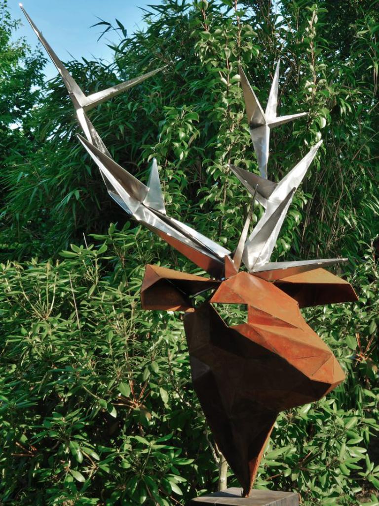 Insolite sculpture polygonale cerf avec insert de brûleur sur une stèle en chêne oxydé pour la maison et le jardin. Le brûleur fourni contient déjà des pierres de lave individuelles, de sorte que ce brûleur peut être facilement rempli de bioéthanol