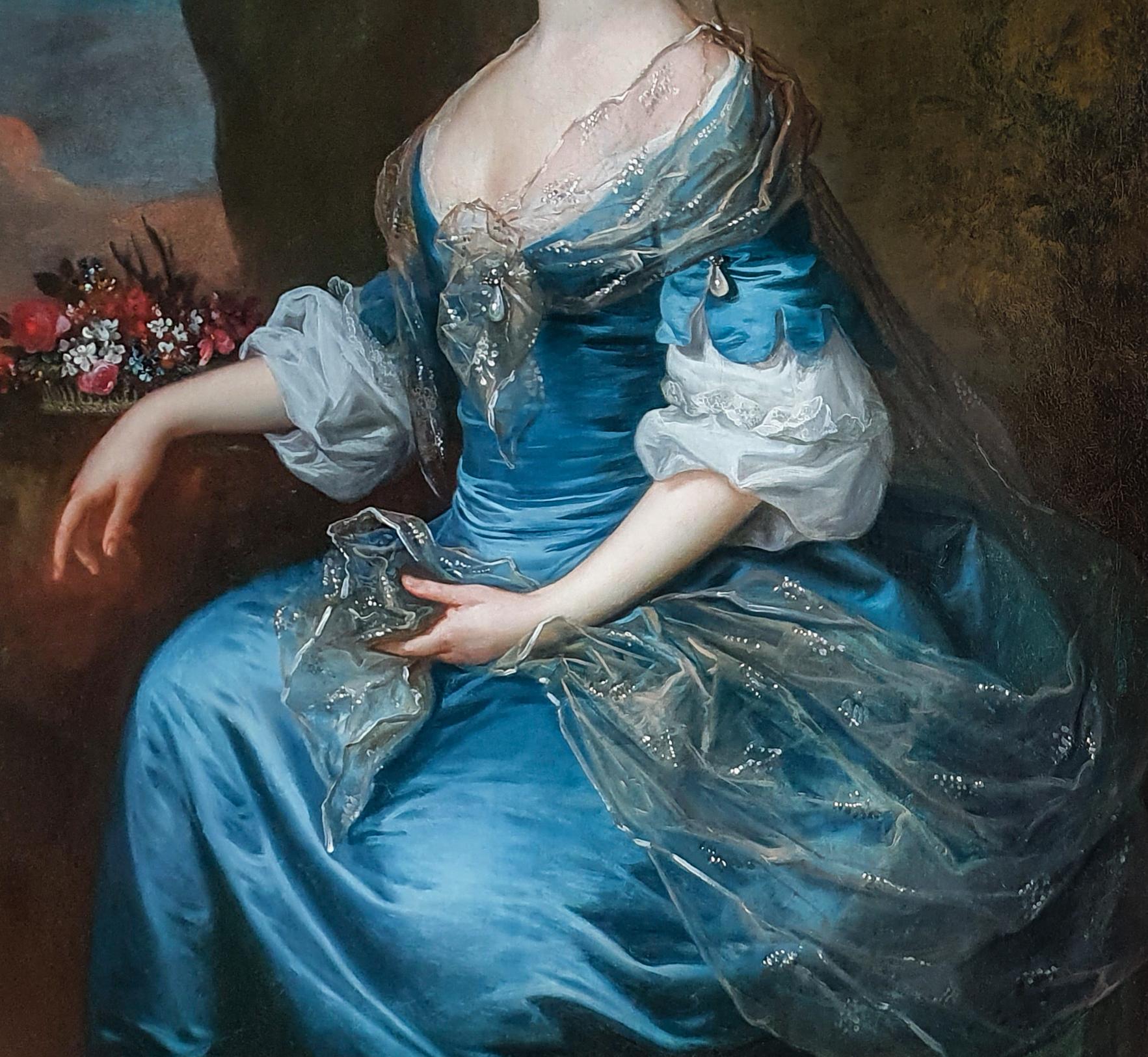 This large-scale portrait is striking in its portrayal of the sumptuous fabrics and their decorative richness.  Beautifully and meticulously rendered throughout, the sitter has been depicted seated in an outdoor setting beside a basket of flowers on
