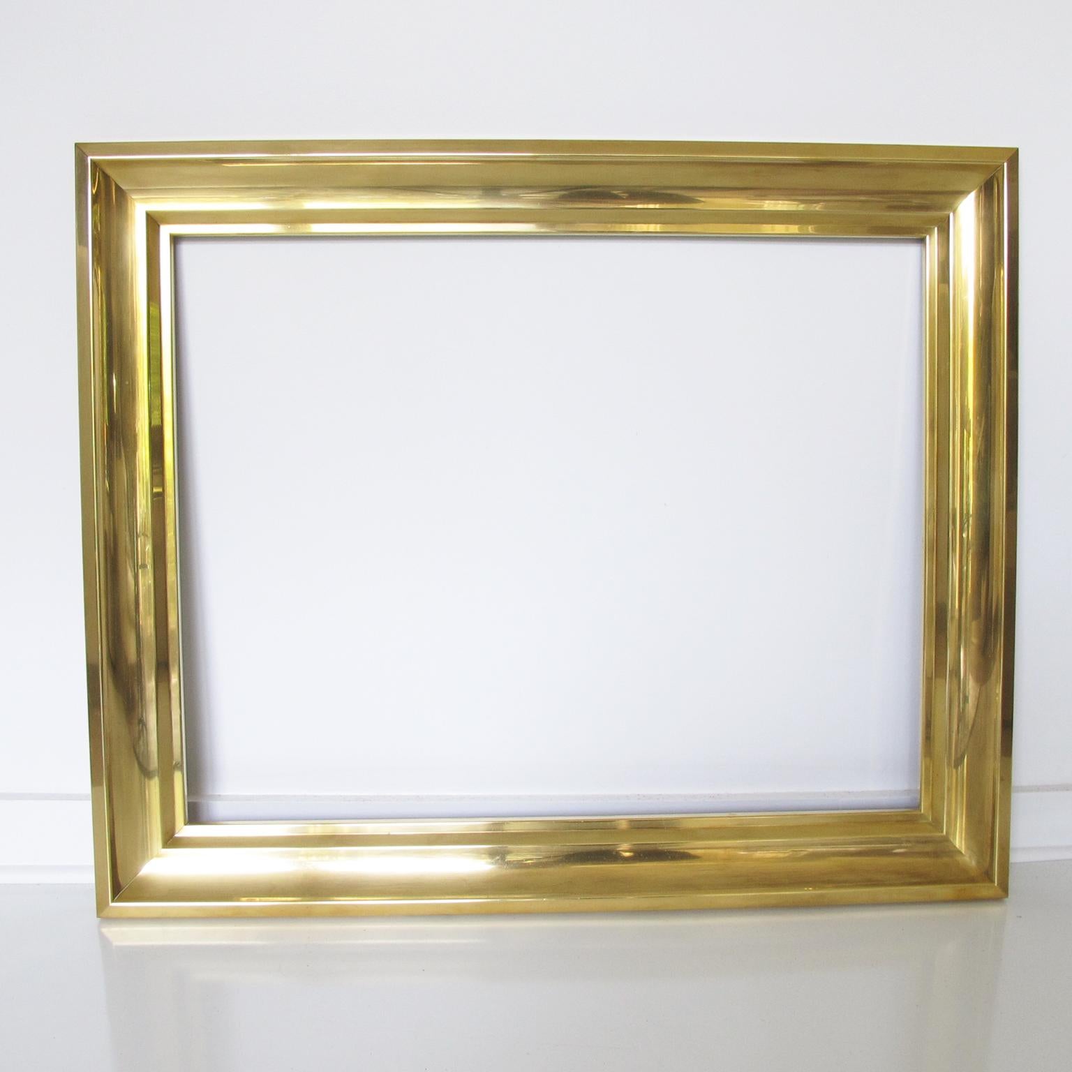 This lovely 1940s French polished brass frame is perfect for paintings, drawings, lithographs, mirrors, or any creative decoration. The frame has a large proportion and can be hung in a portrait or landscape position. The gilded brass frame has a