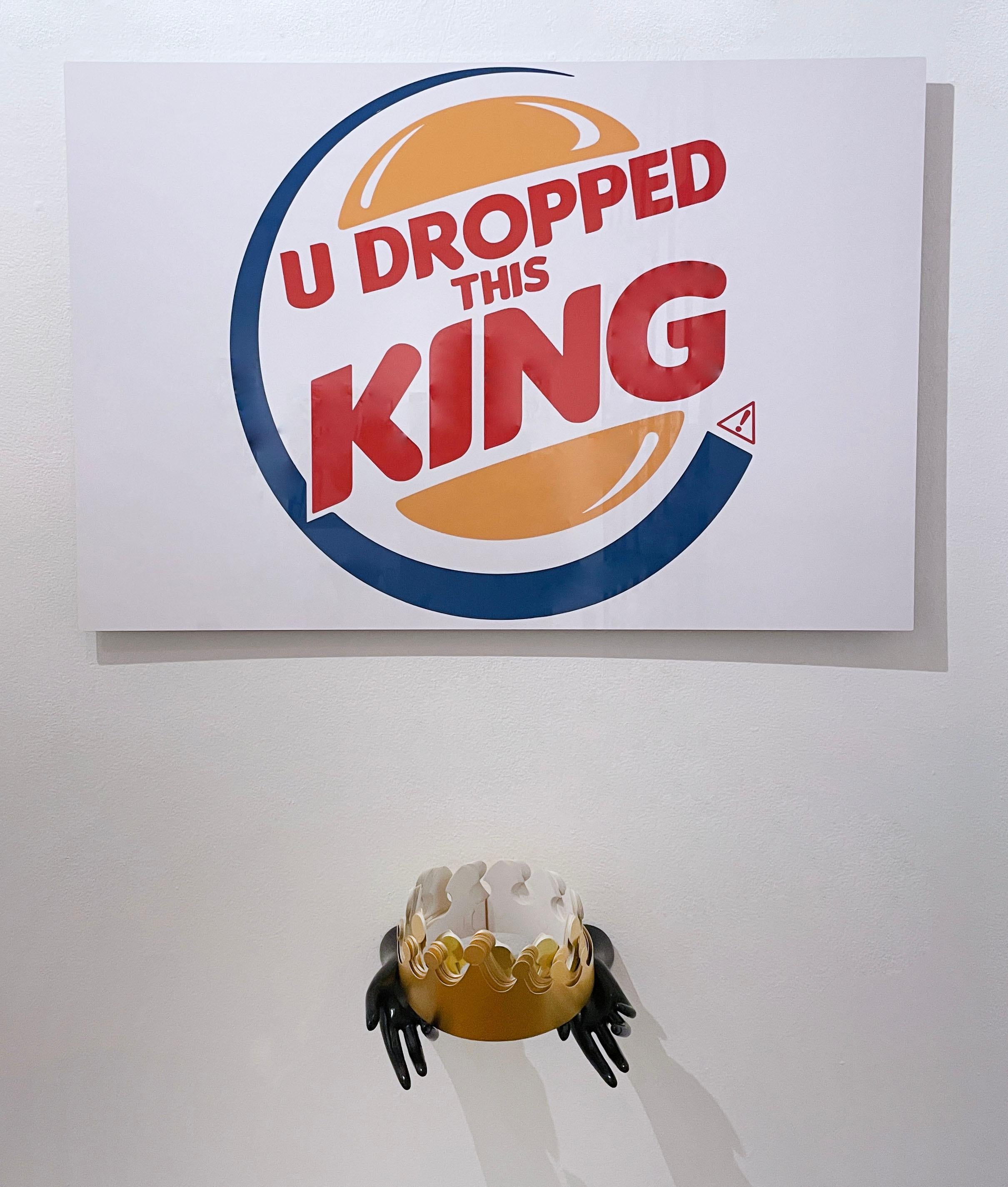 "U Dropped This King" (2022) von Straßenkünstler Kid Hazo
24 x 36 x .75"
Mit Puppenhänden und Papierkrone (9,5 x 10,5 x 9")

Archivtinte auf Aluminium. Zeichenkunst, Satire, Text, Anspielung auf das Burger King-Logo. Rot, gelb, blau und weiß.