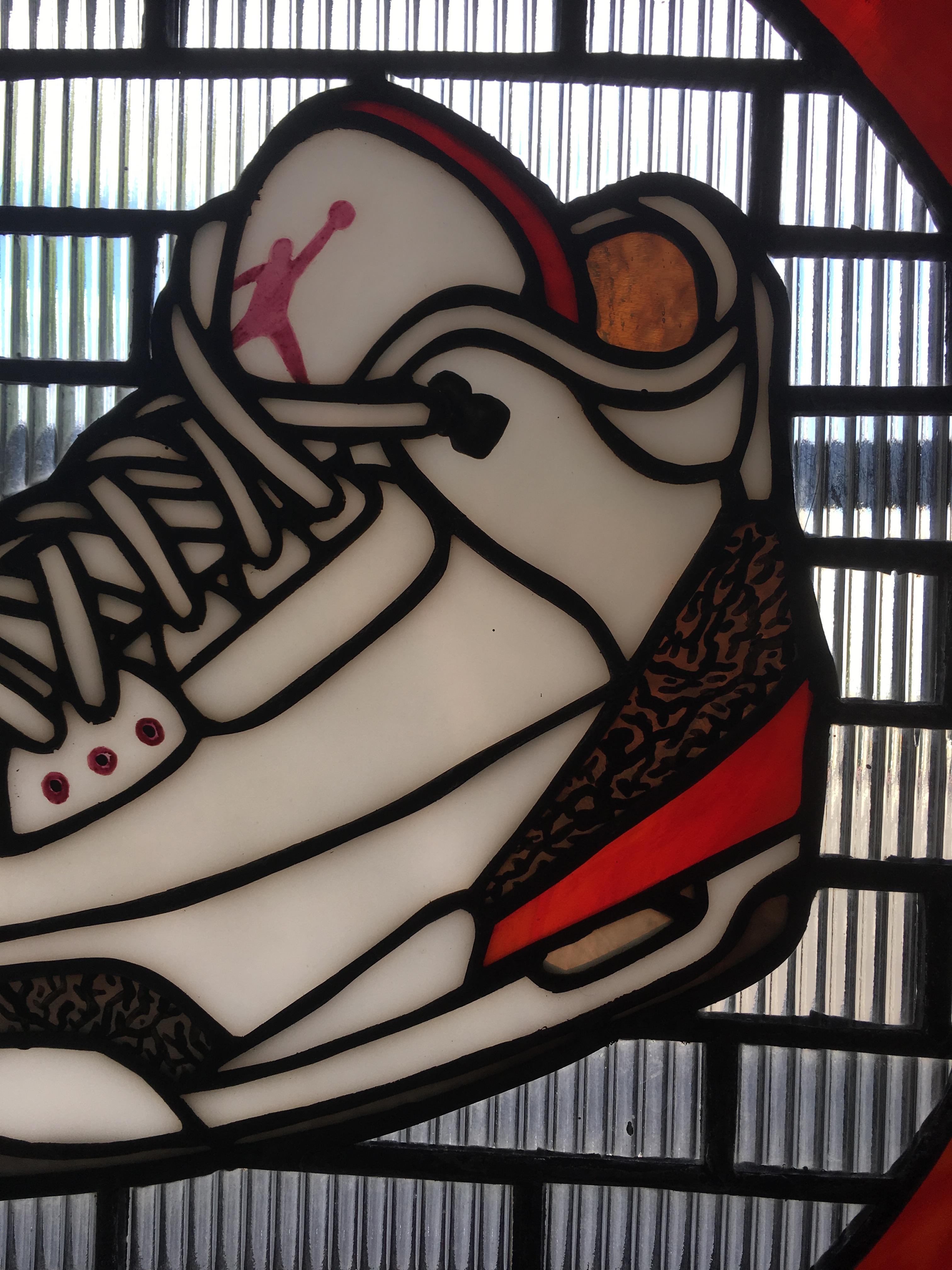 Handcrafted by TF Dutchman, Jordan III is a one of a kind original  stained glass panel. A detailed rendition of the classic Nike, Air Jordan III. White, gray, red, and clear textured glass are enhanced by a kiln fired Jordan Jumpman. The