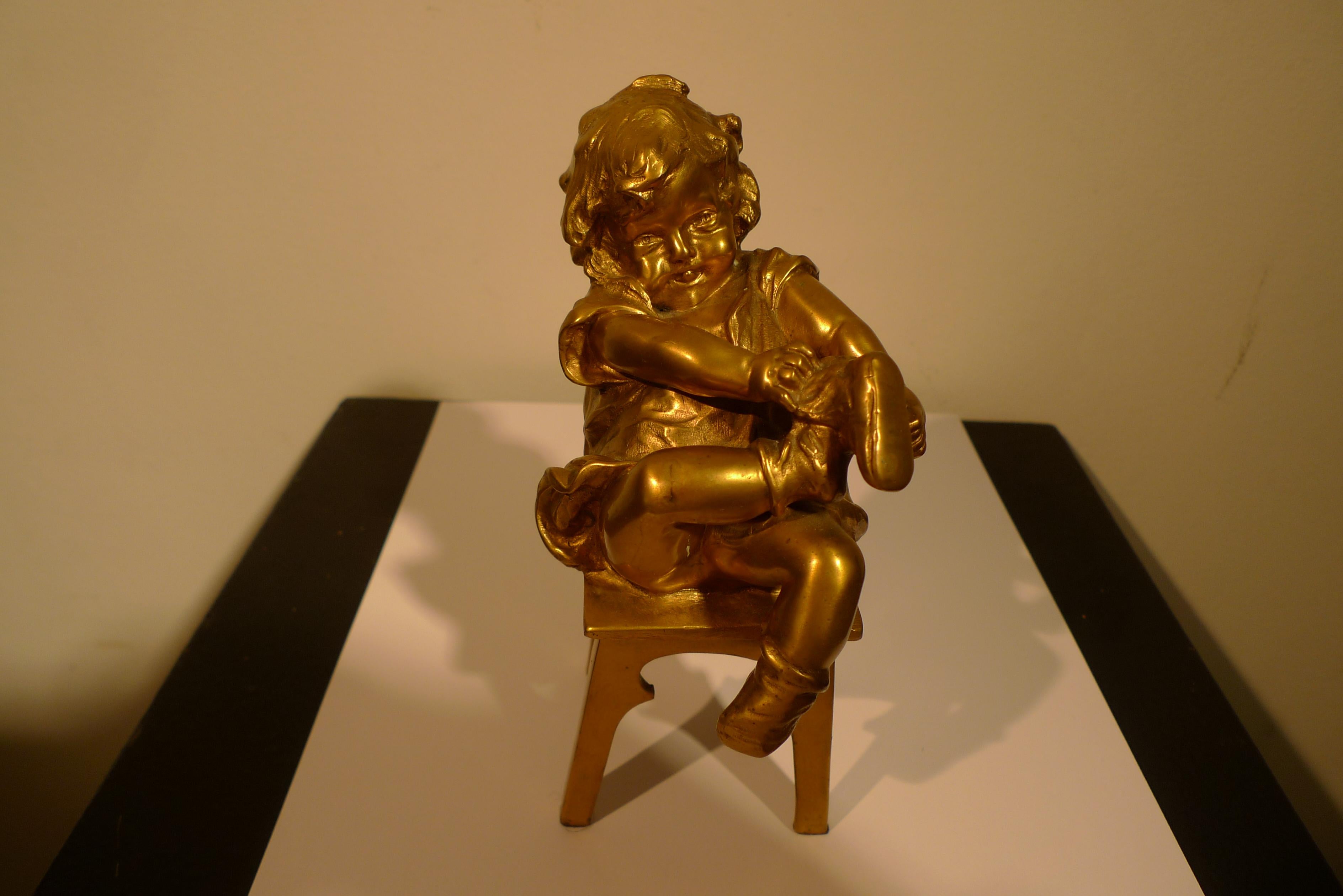 "Niña sentada en un taburete atándose el zapato", Bronce del siglo XX de Juan Clará