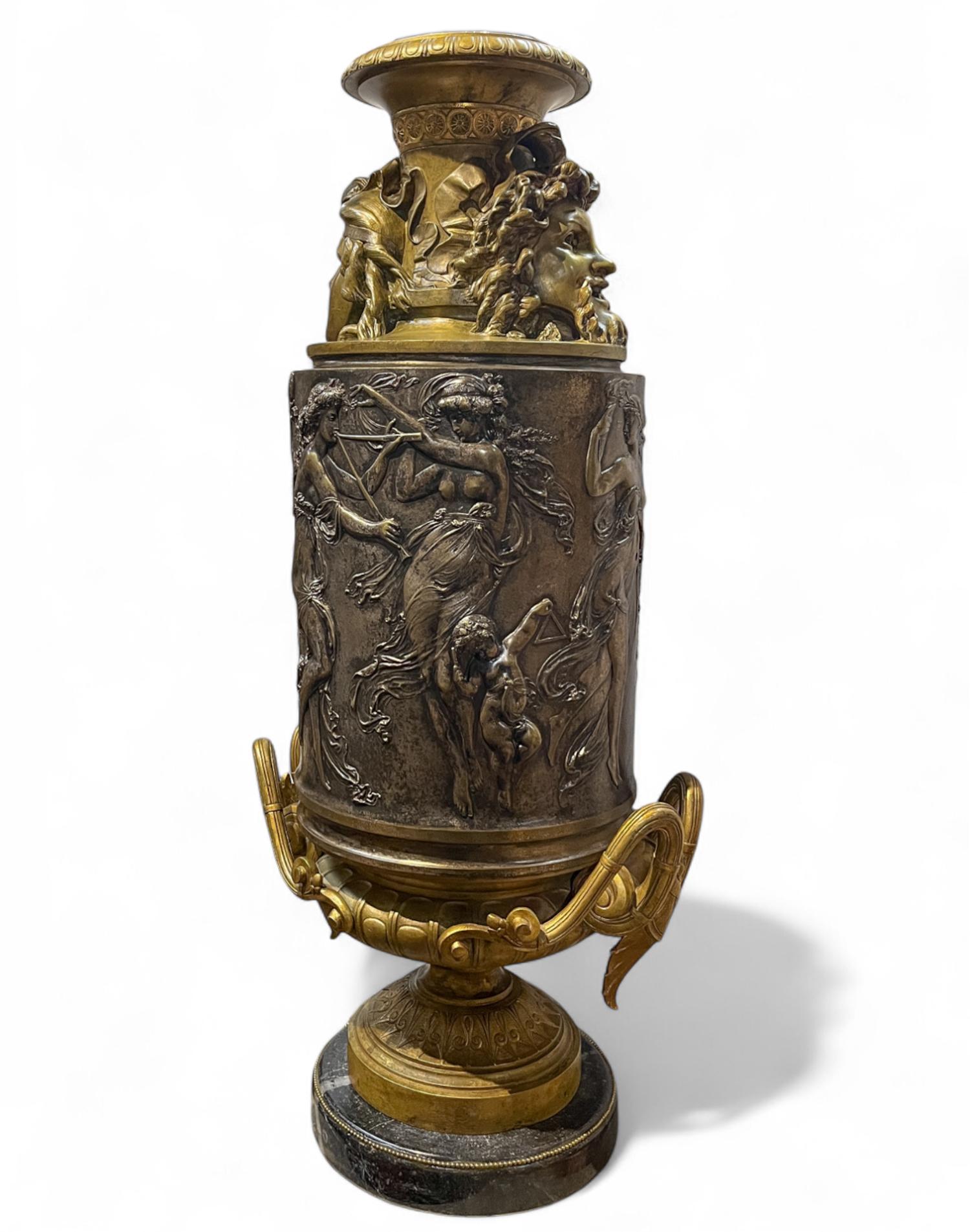 Large Neoclassical French Gilt and Silvered Bronze Two Handle Vase

A large cylindrical vase with a silvered body and gilt neck and base. Topped by two masks, one modeled after the face of Zeus. The body adorned with a continuous scene of dancing