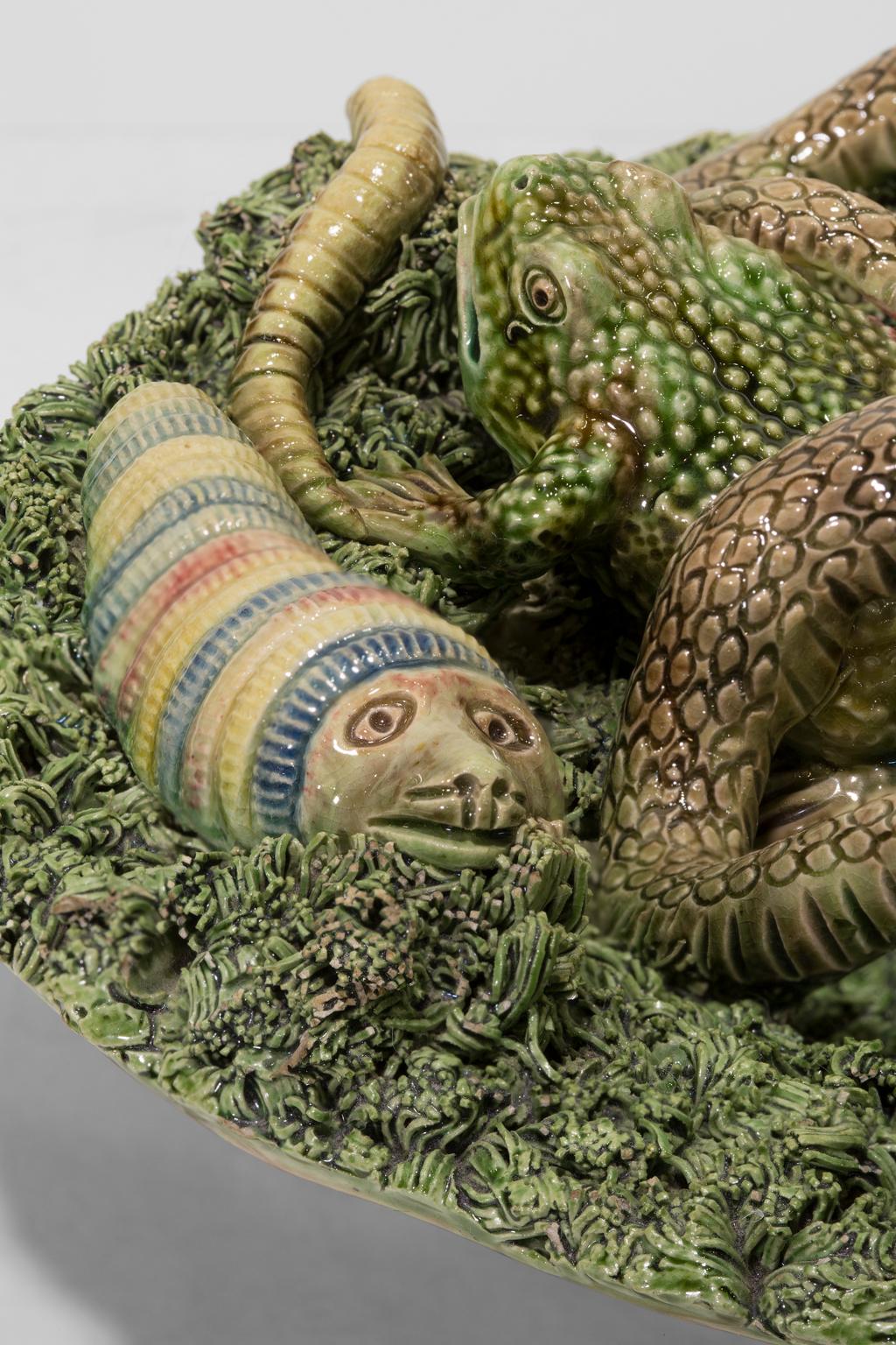 Cette assiette en majolique portugaise Palissy de Jose A Cunha représente un serpent, une araignée, une grenouille, une chenille et un papillon sur un fond vert d'argile déchiquetée. La pièce porte les marques de fabrique de la poterie Jose A Cunha.