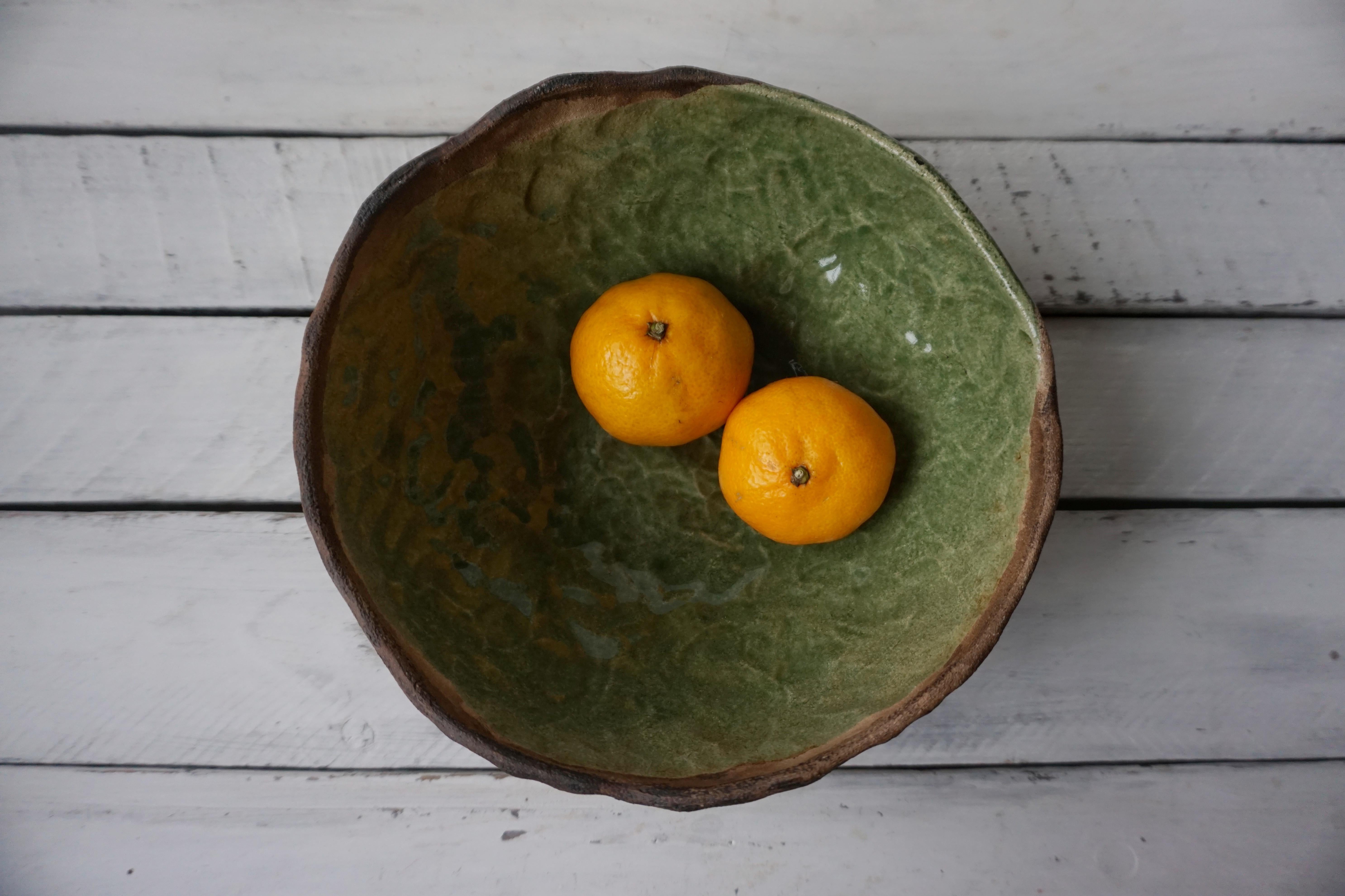This rustic green ceramic bowl is handmade by Ukrainian artist Kate Voronina based in Ukraine. The bowl is made in a traditional hand-built technique without a potter's wheel with a milk glaze. That's why it has an incredible texture - you can