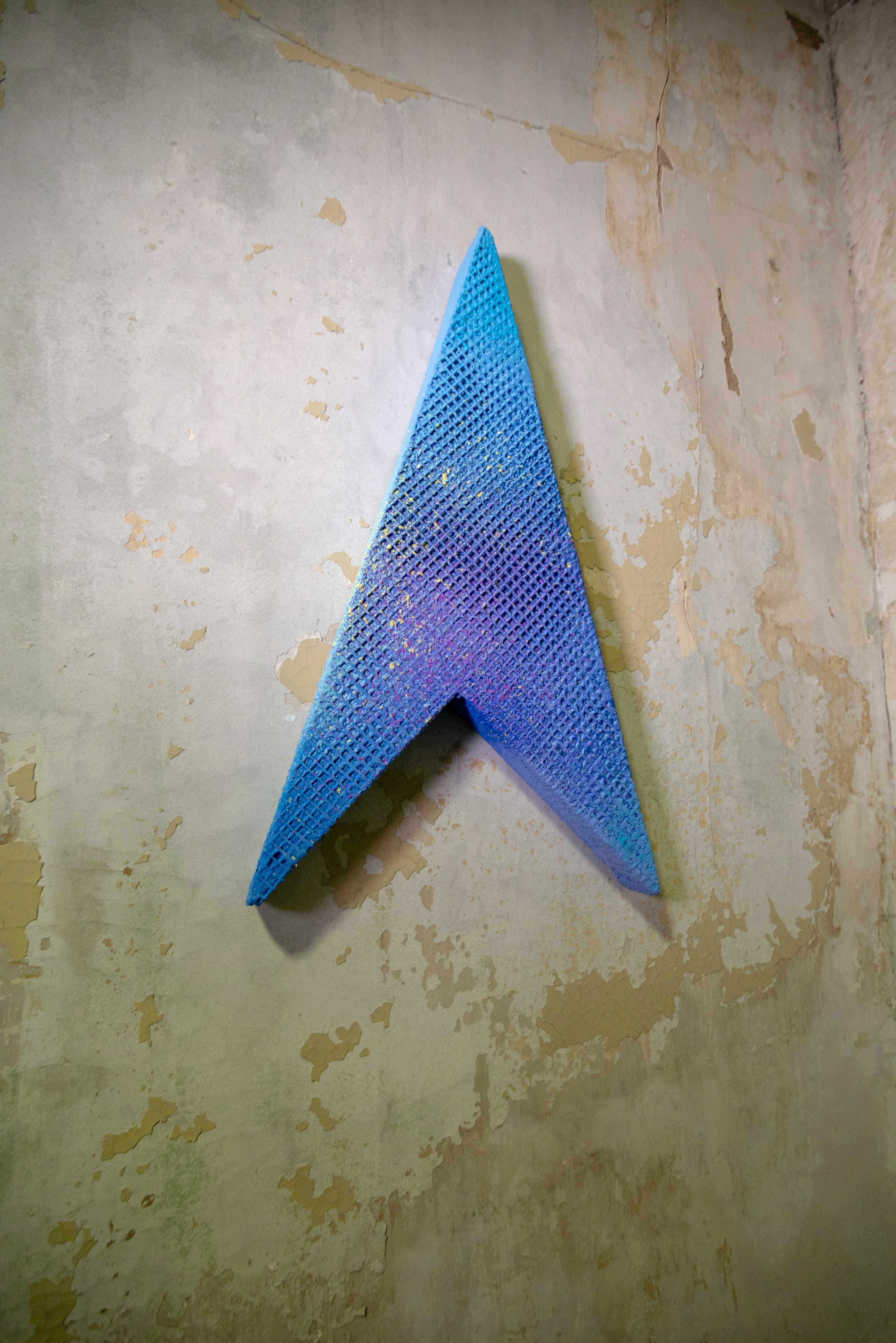 This piece is in a triangular arrow-looking shape in a blue tone, hence its name Blue Arrow. The piece is done in mixed media to create different tones and textures. The piece overall has a grid-like texture to it with a heavy blue tone and a purple