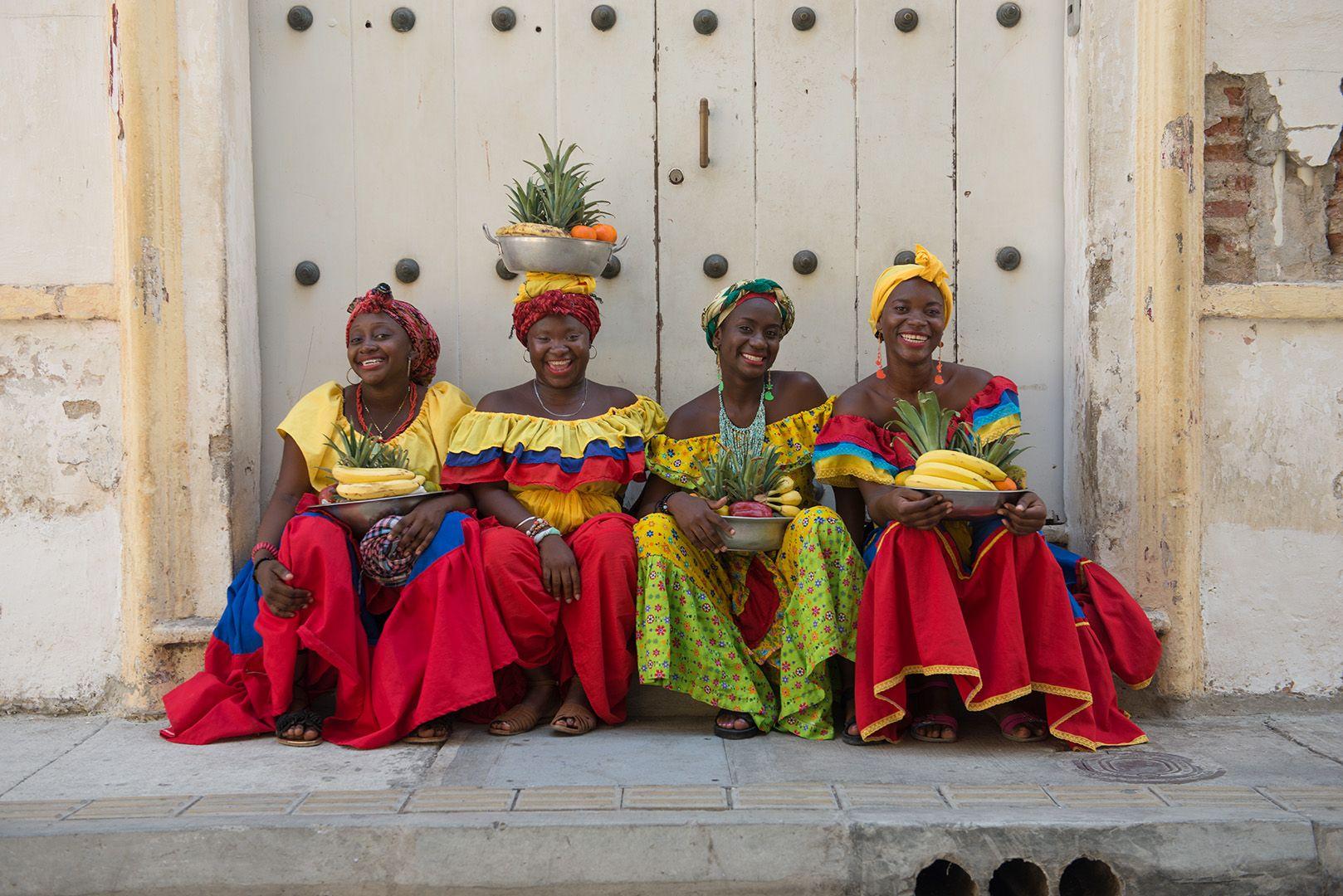 Lou Vest Color Photograph - Four Palenqueras - Cartagena, Colombia fruit sellers in red, yellow & blue