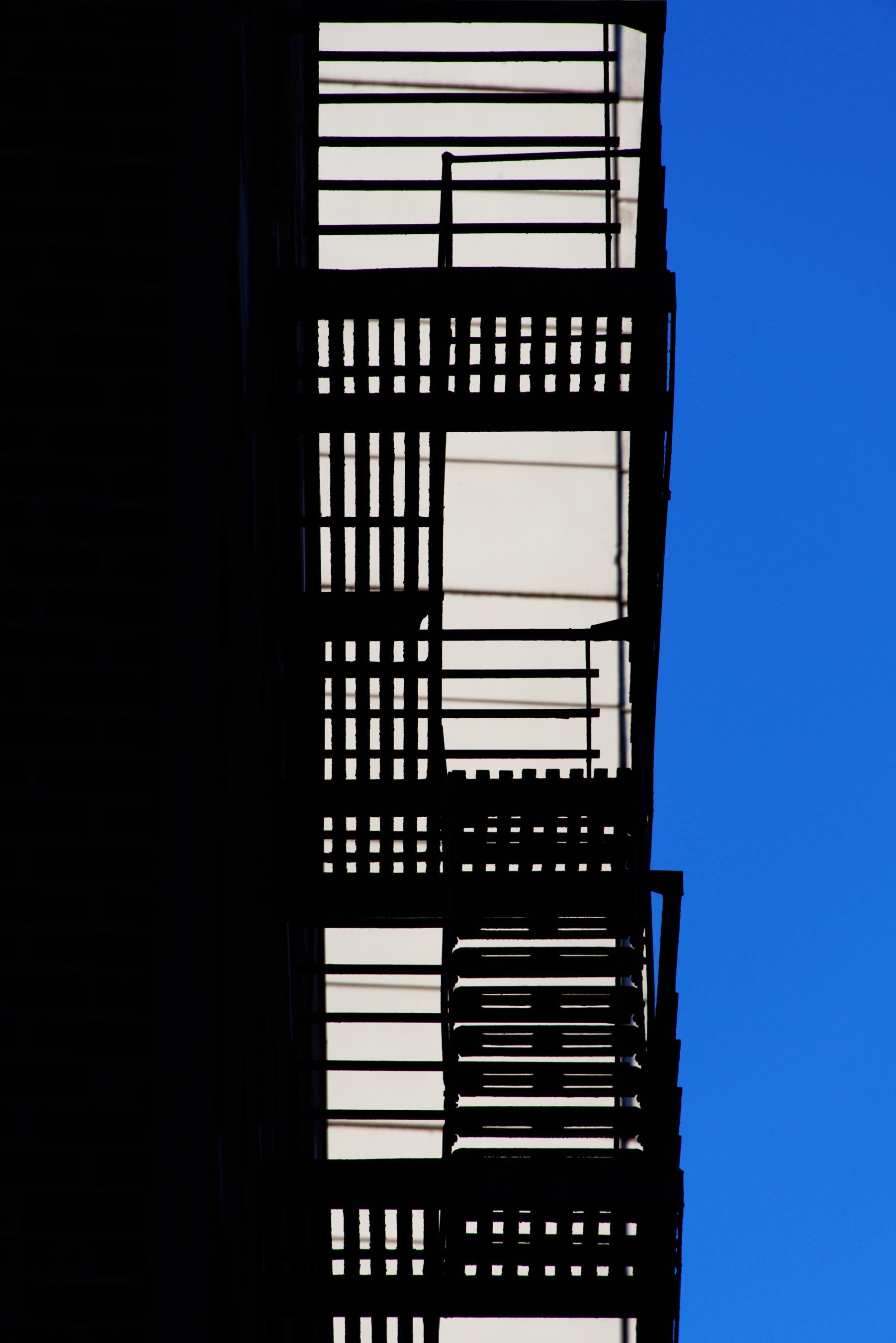 Bob Krasner Color Photograph – „“Fire Escape““, Fotografie, Stadt, Architektur, Geometrie, Muster, Treppe, Blau