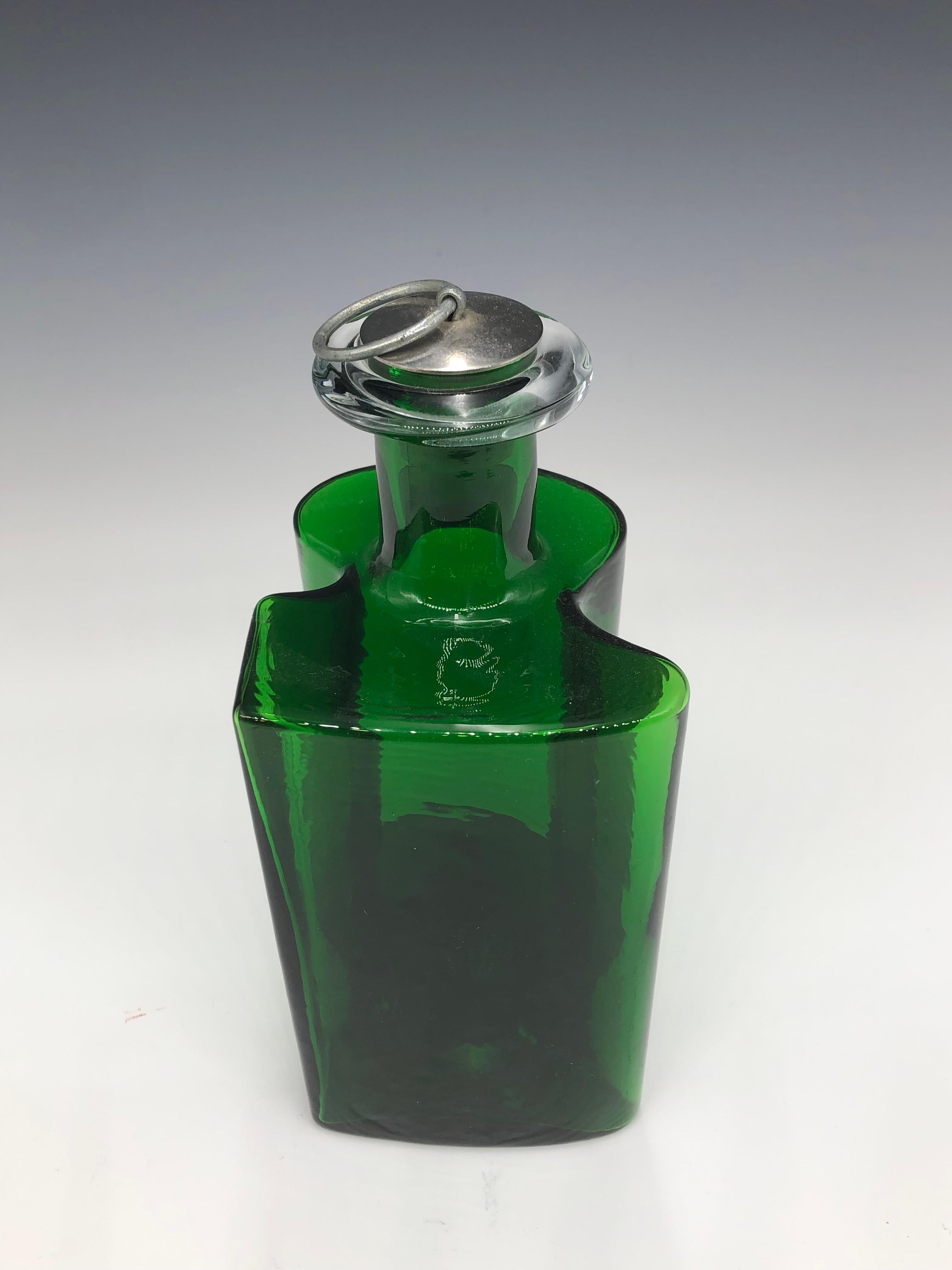 Gorgeous vintage 1970s Danish Modern glass decanter with metal ring pull cork stopper. Made by Holmegaard of Denmark and designed by Hjördis Olsson & Charlotte Rude, as part of Holmegaard's Hivert Line.

This deep emerald green Hiverten bottle