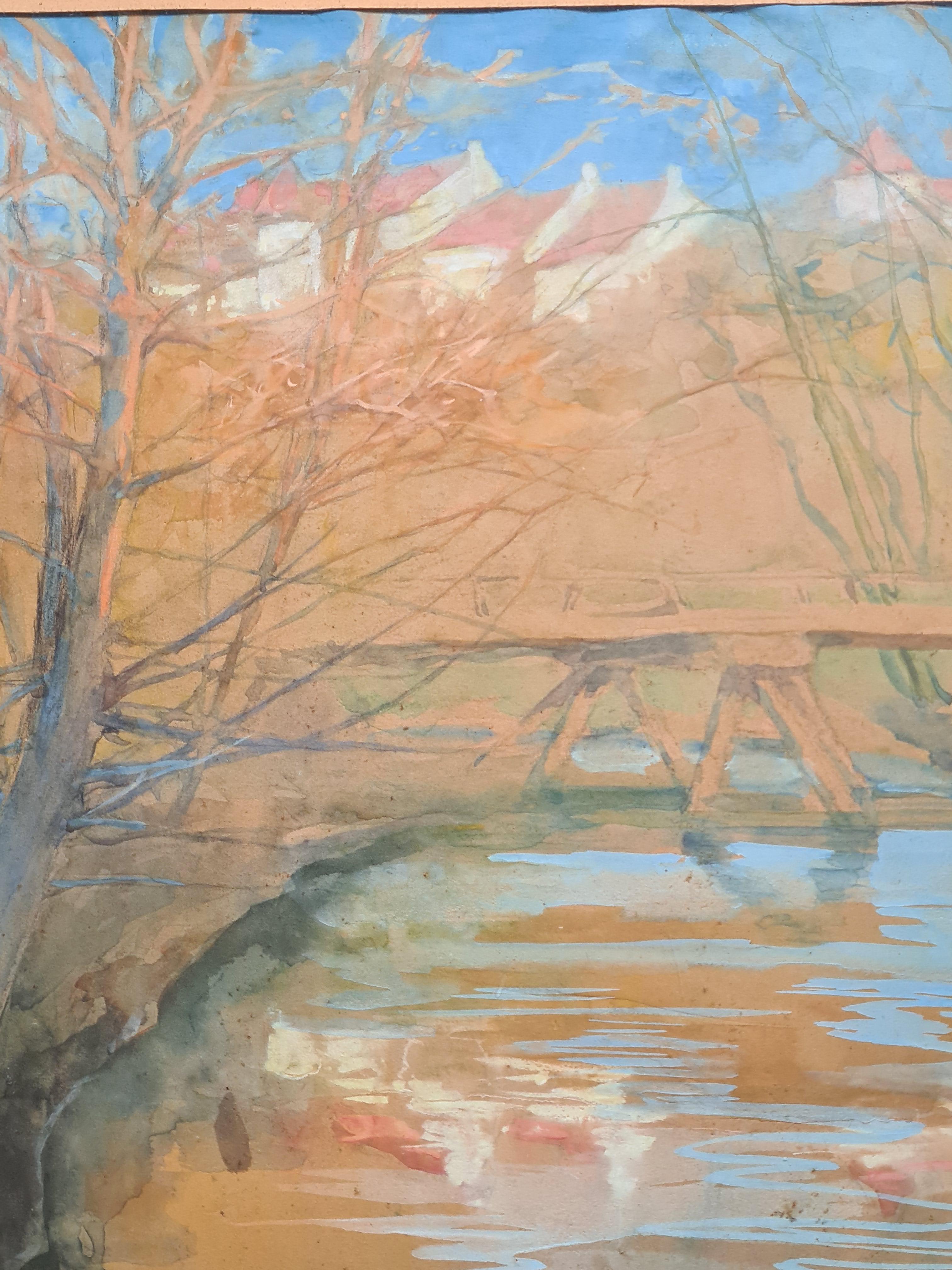 Early 20th century watercolour on paper of a tranquil river, bridge and village scene. The painting is presented in a plain wood frame under glass. 

This charming watercolour portrays a serene landscape dominated by a calm river reflecting the