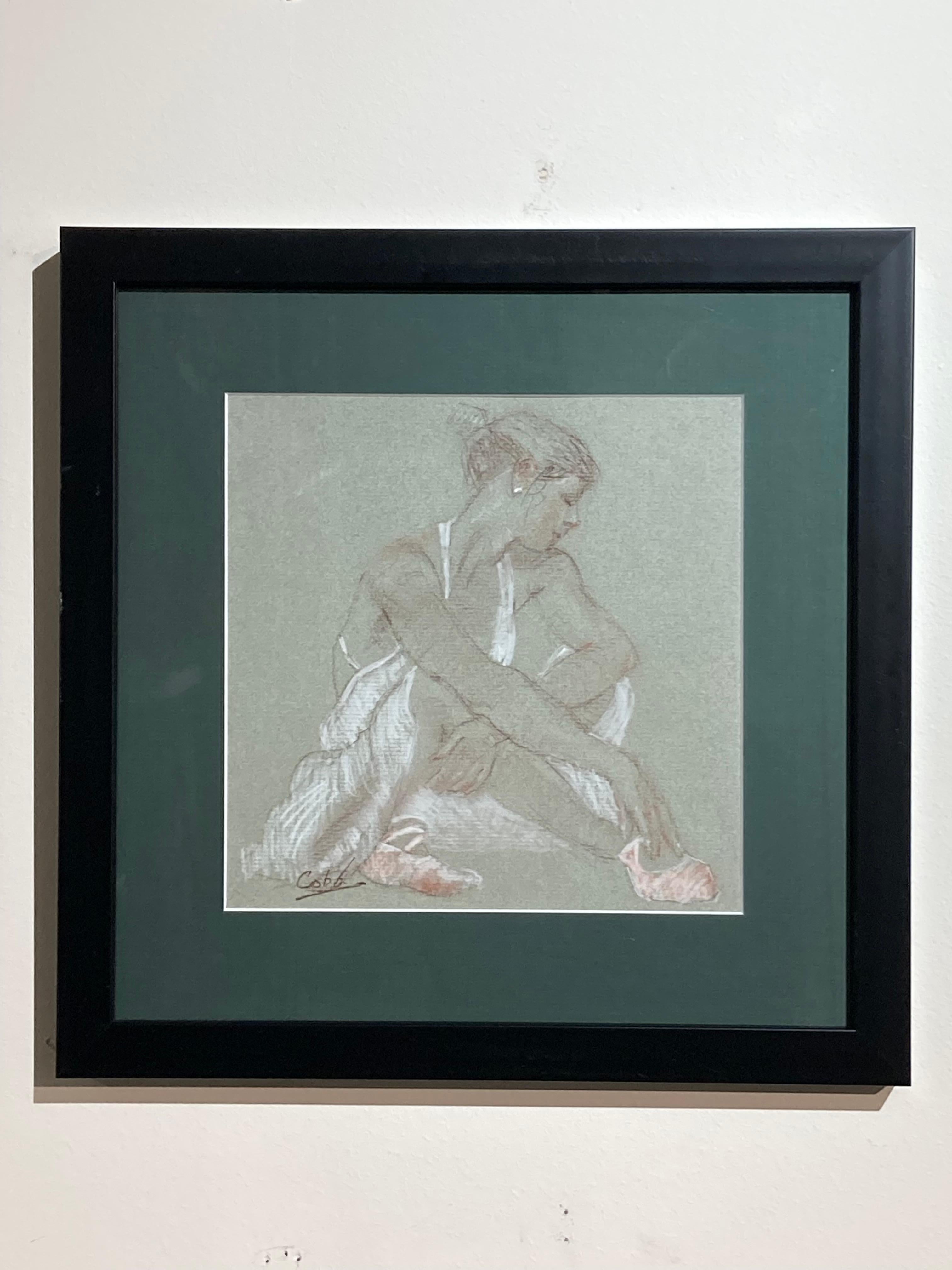 Diese gerahmte 13,5" x 13,5" große Kohle- und Konterzeichnung des Künstlers James Cobb zeigt eine Ballerina in einer sitzenden, entspannten Pose. Die Arbeit ist auf  getöntes graues Zeichenpapier hinter einem dunklen Salbei-Passepartout in einem