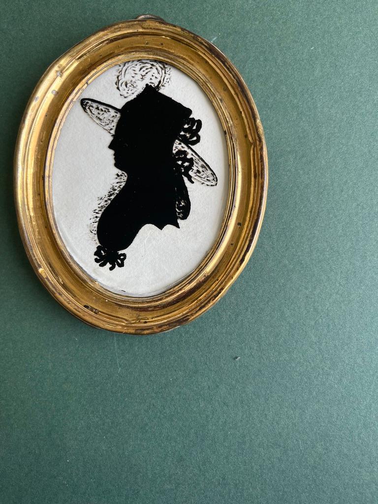 Silhouette finement détaillée d'une dame de l'époque victorienne, exceptionnellement représentée portant un chapeau élaboré avec un bord en dentelle et un panache.

Cercle de Hinton Gibbs (1783-1839)
Portrait d'une dame, en buste, tournée vers la