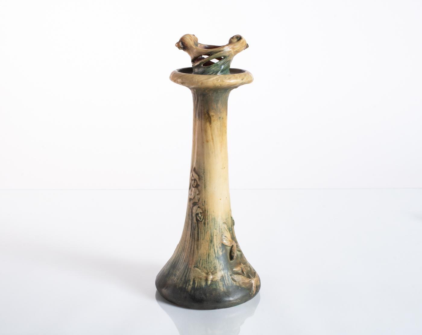 Bone-colored two-headed candlestick featuring faces, moths, and stars in a design presented at the 1900 Exposition Universelle (World’s Fair) held in Paris. Titled "The Magic of Fire Light" and part of the "Fates" Series. Stamped Amphora in the