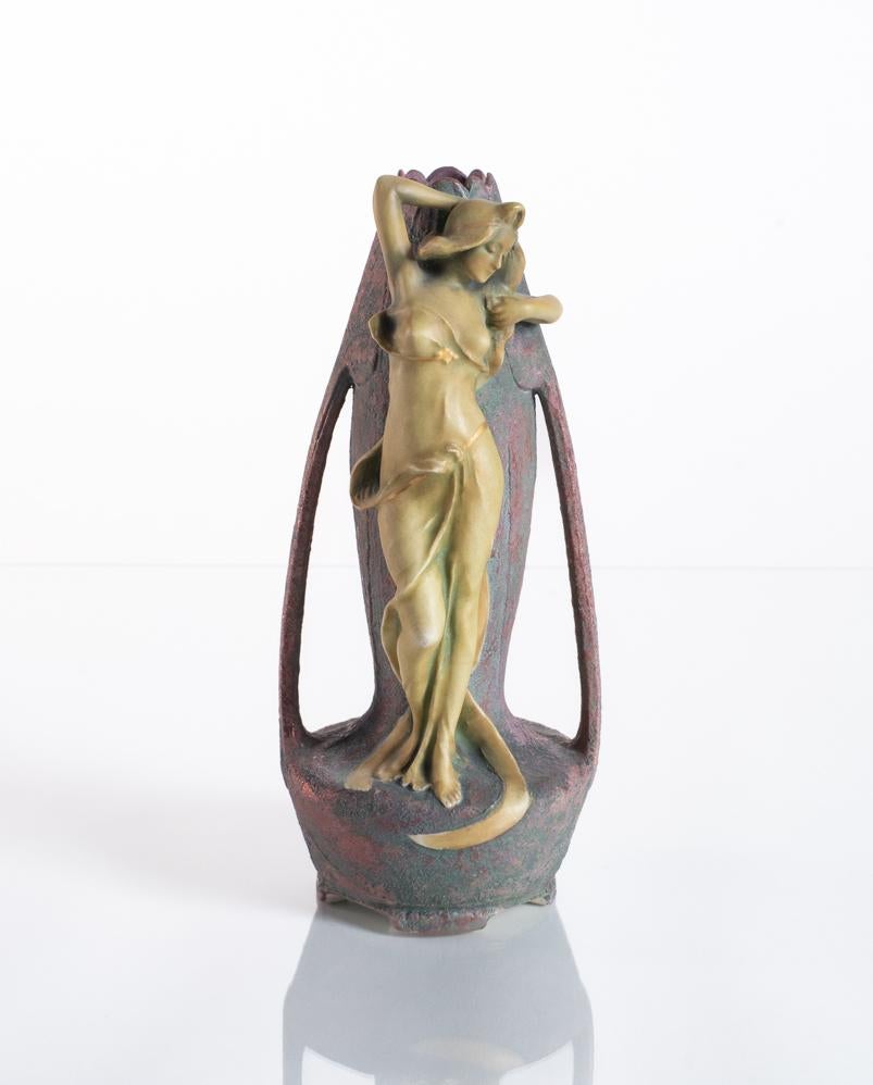 Figural vase with a golden maiden on an iridescent form. This vase features a beautiful juxtaposition of the smooth and sinuous texture of the woman against a psychedelic stone-like stylized tulip vessel.

Already well established throughout Europe