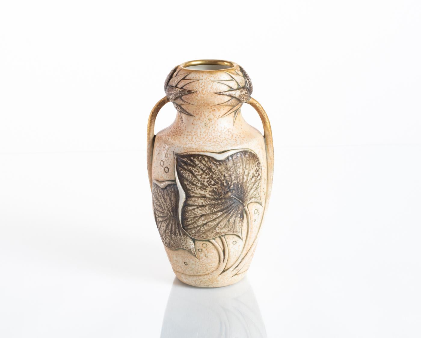 Earthy, textured water lily leaf vase with gilted, figural stem arms which encircle the golden mouth of the piece with their flowers. Stamped Ernst Wahliss and numbered in the base. This design is attributed to Paul Dachsel. 

Already well