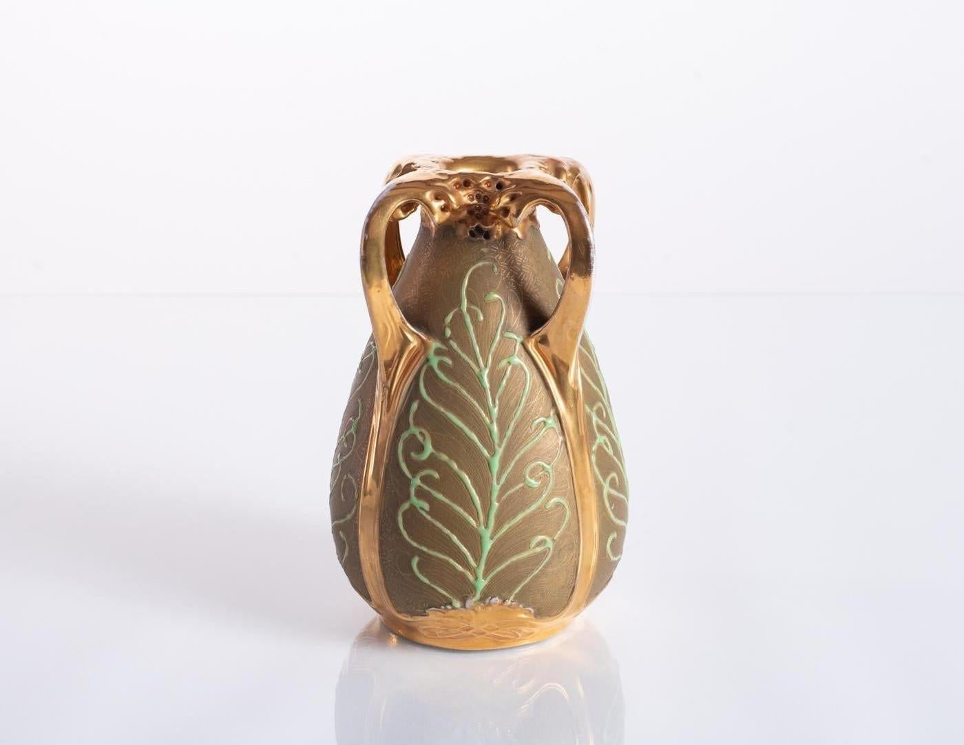 Keramikvase, entworfen von Paul Dachsel für Amphora, mit zarten goldenen Kreuzschraffuren und Reliefelementen, die an Pfauenfedern erinnern. Polierte Goldglasur um die Öffnung, an den Griffen und am Bodenrelief. Ein Paul Dachsel zugeschriebener