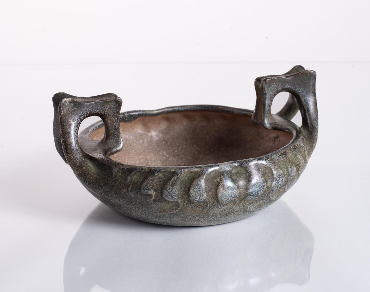 A shallow naturalistic bowl with organic bone-like design elements and a mottled glaze of blue, gray, and green. Stamped Amphora in the base, and numbered; added RStK bottom marking indicates this piece was hand-finished on the potter's wheel.