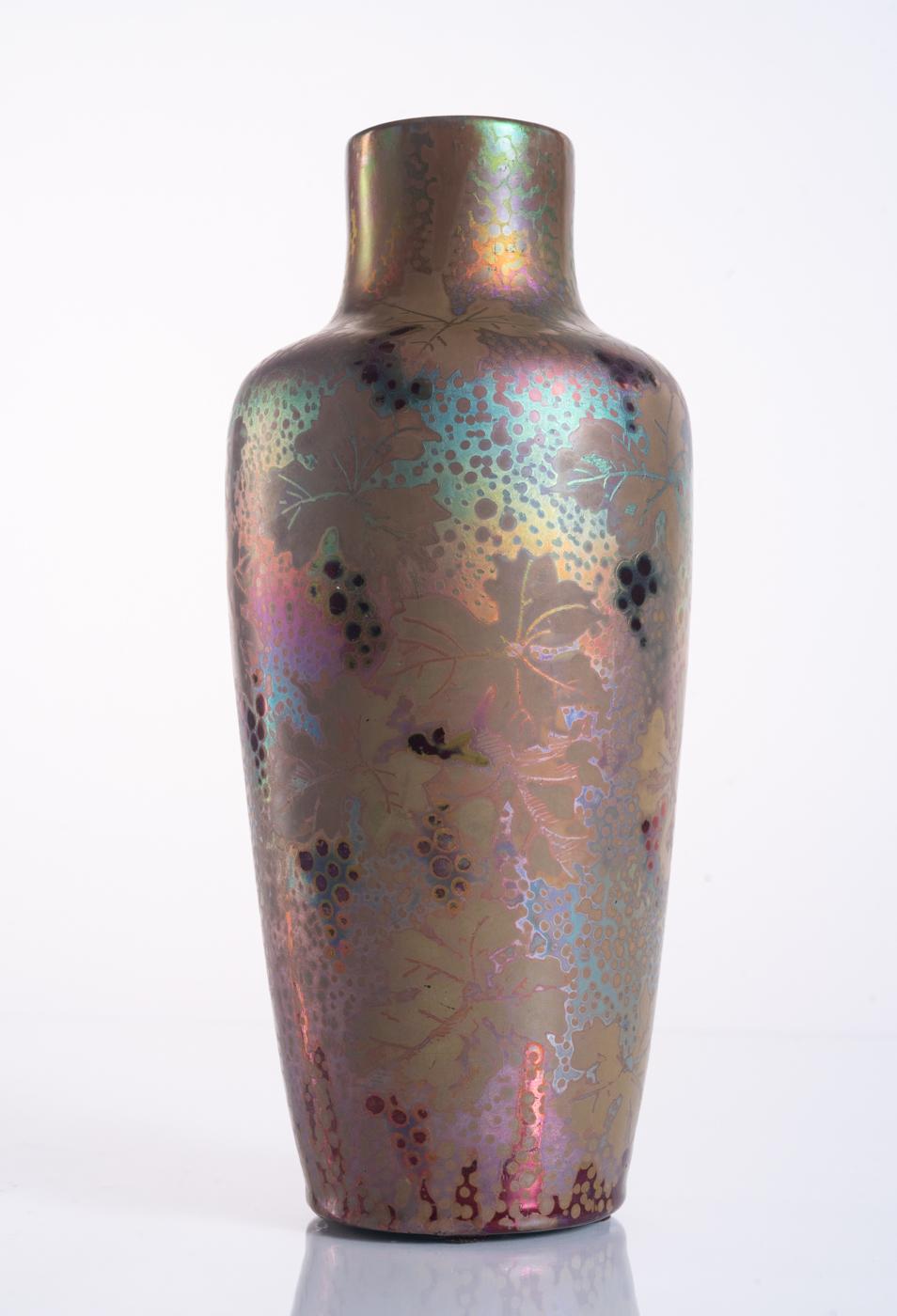Ceramic vase in a blue and green metallic lustre glaze by master of iridescence Clement Massier, with clusters of grapes and leaves in deep purple. Signed MCM in the base, and numbered. 

Clément Massier was a renowned French ceramicist known for