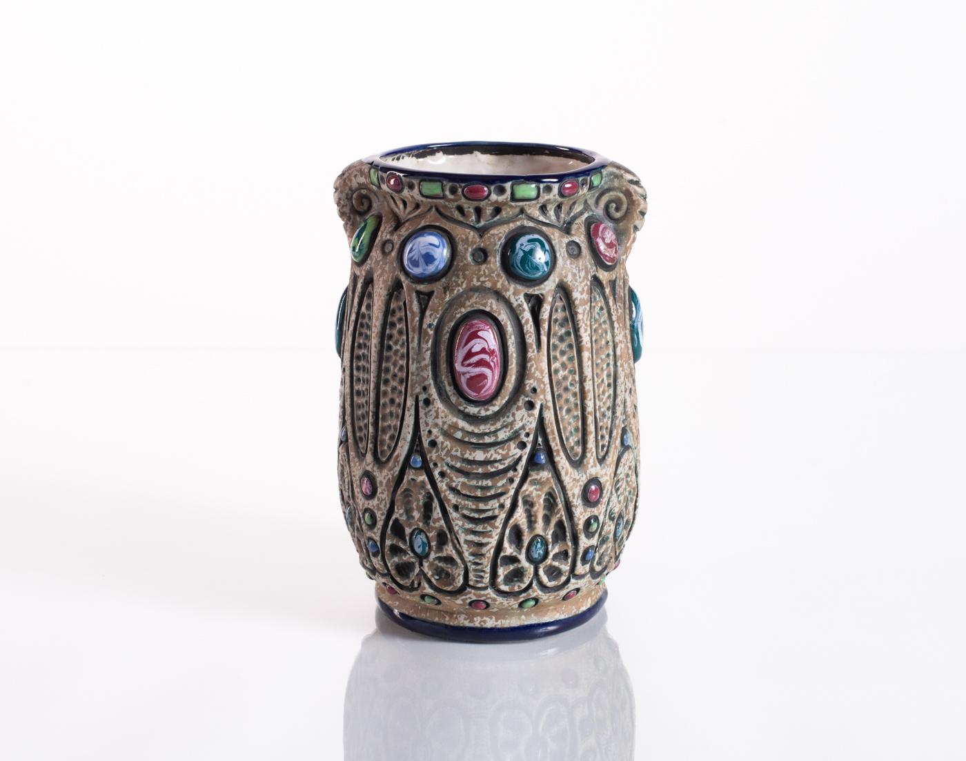 Carved folk art vase, with hand-painted bright cloisonné enamel embellishments. The form's contrasting glazes amplify its intricate carvings and mottled texture. Stamped Amphora in the base, and numbered.

Riessner, Stellmacher and Kessel (RStK),