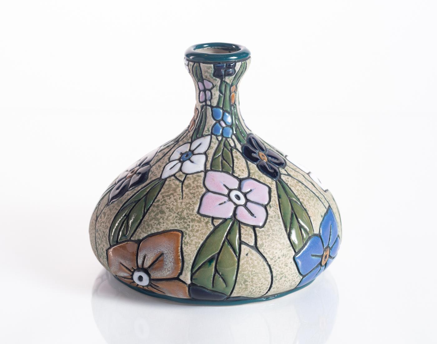 A colorful ceramic vase with hand-painted flowers in bright cloisonné enamels. Stamped Amphora in the base, and numbered.

Riessner, Stellmacher and Kessel (RStK), later known as Amphora, began producing luxury ceramic objects in Turn-Teplitz,