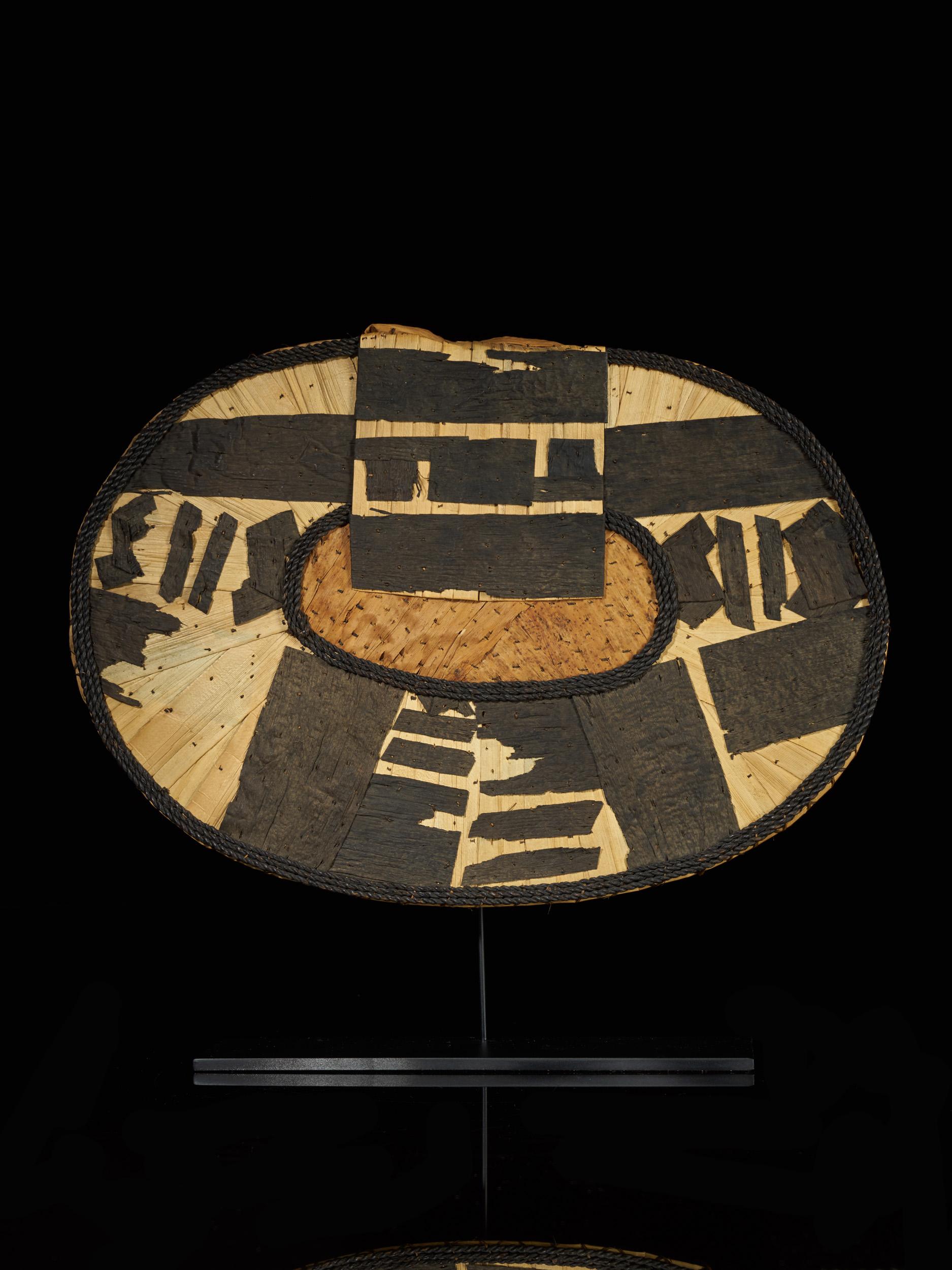 Back aprons (negbe, pl. egbe) were trendy among upper-class Mangbetu women at the turn of the twentieth century. This distinctive kidney-shaped ornament pad was built up of intricately layered banana leaves. Worn on special occasions, egbe were
