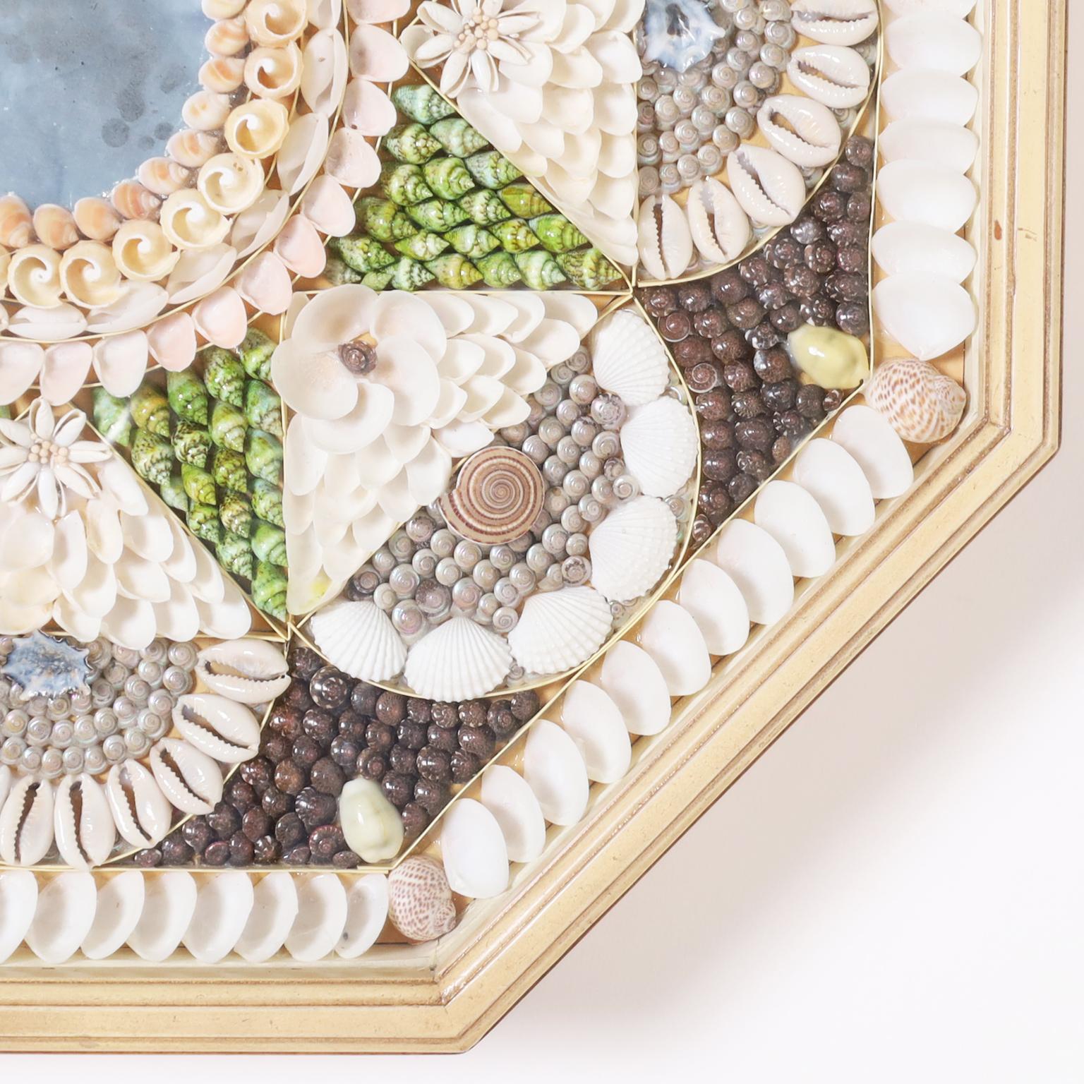 Charming sailors valentine hand crafted in an ambitious composition of exotic sea shells with a distressed mirror at the center, presented in an octagon form shadow box.