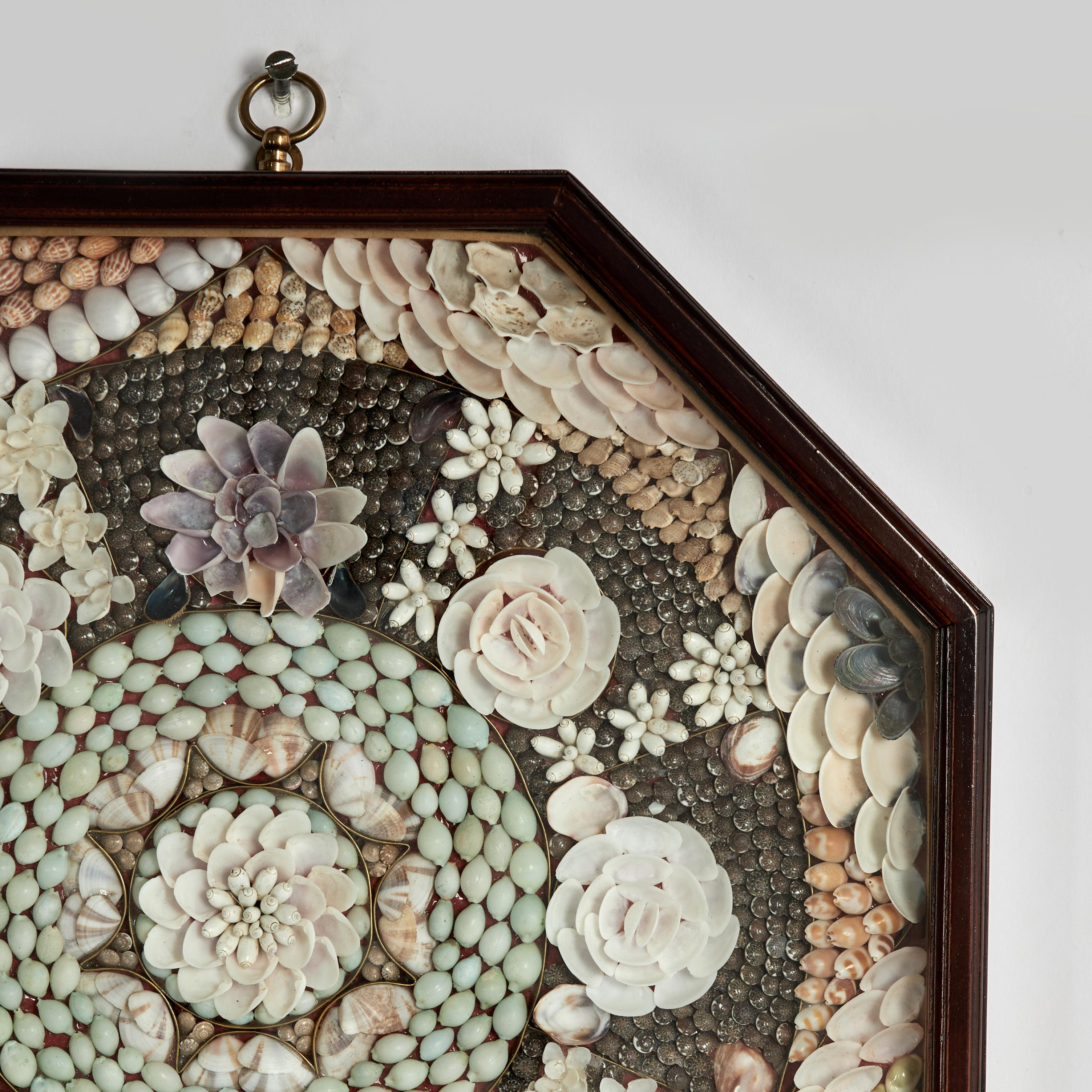 Lofty vintage sailors valentine handcrafted in exotic organic seashells in a delightful composition of floral designs. Presented under glass in an octagon mahogany shadow box.