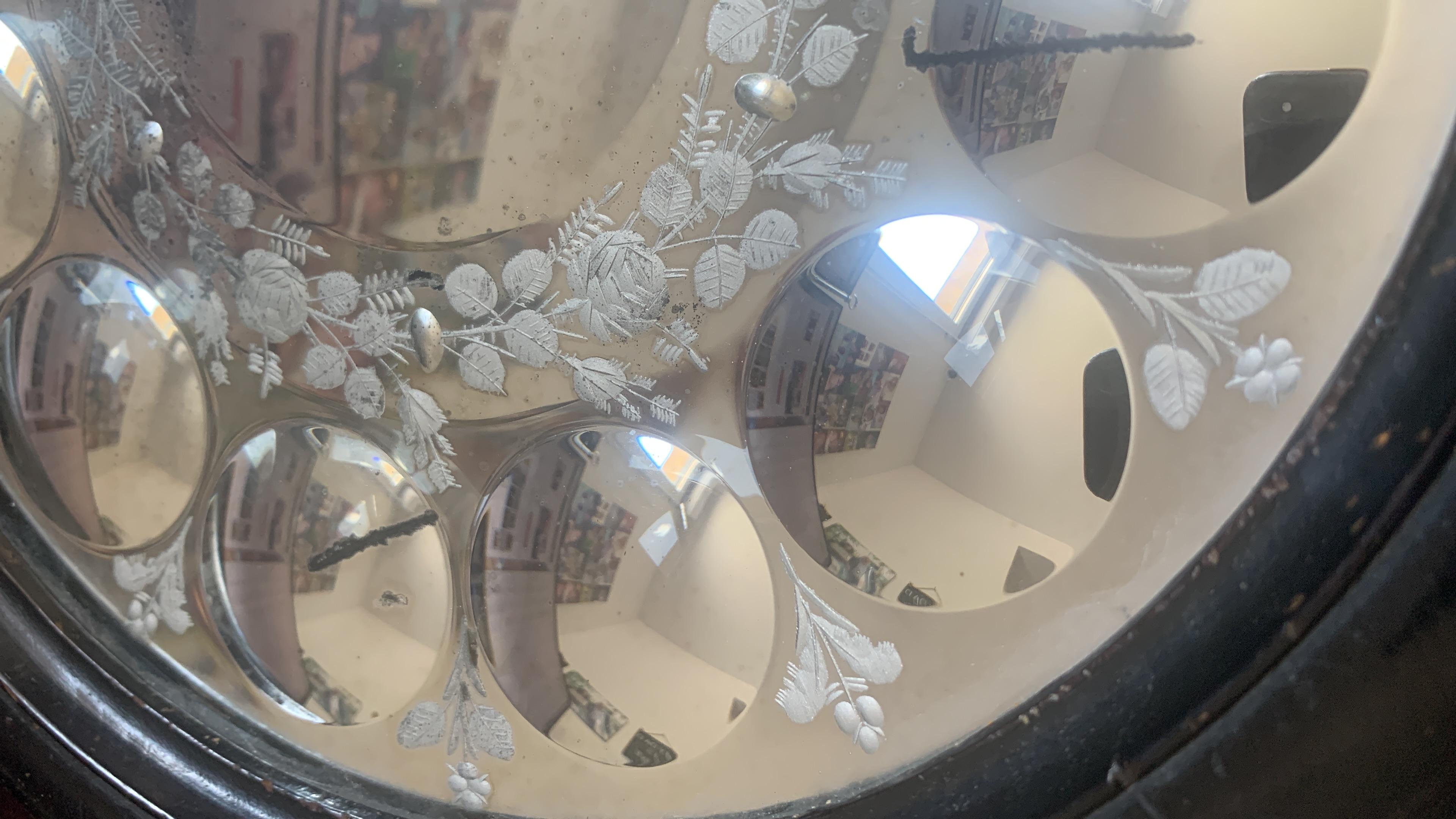 An original Sorcerer's mirror from the 1900's with twelve convex mirrors surrounding a larger convex central mirror decorated with etched roses and foliage. An impressive size with some signs of wear in place which is to be expected for its age.