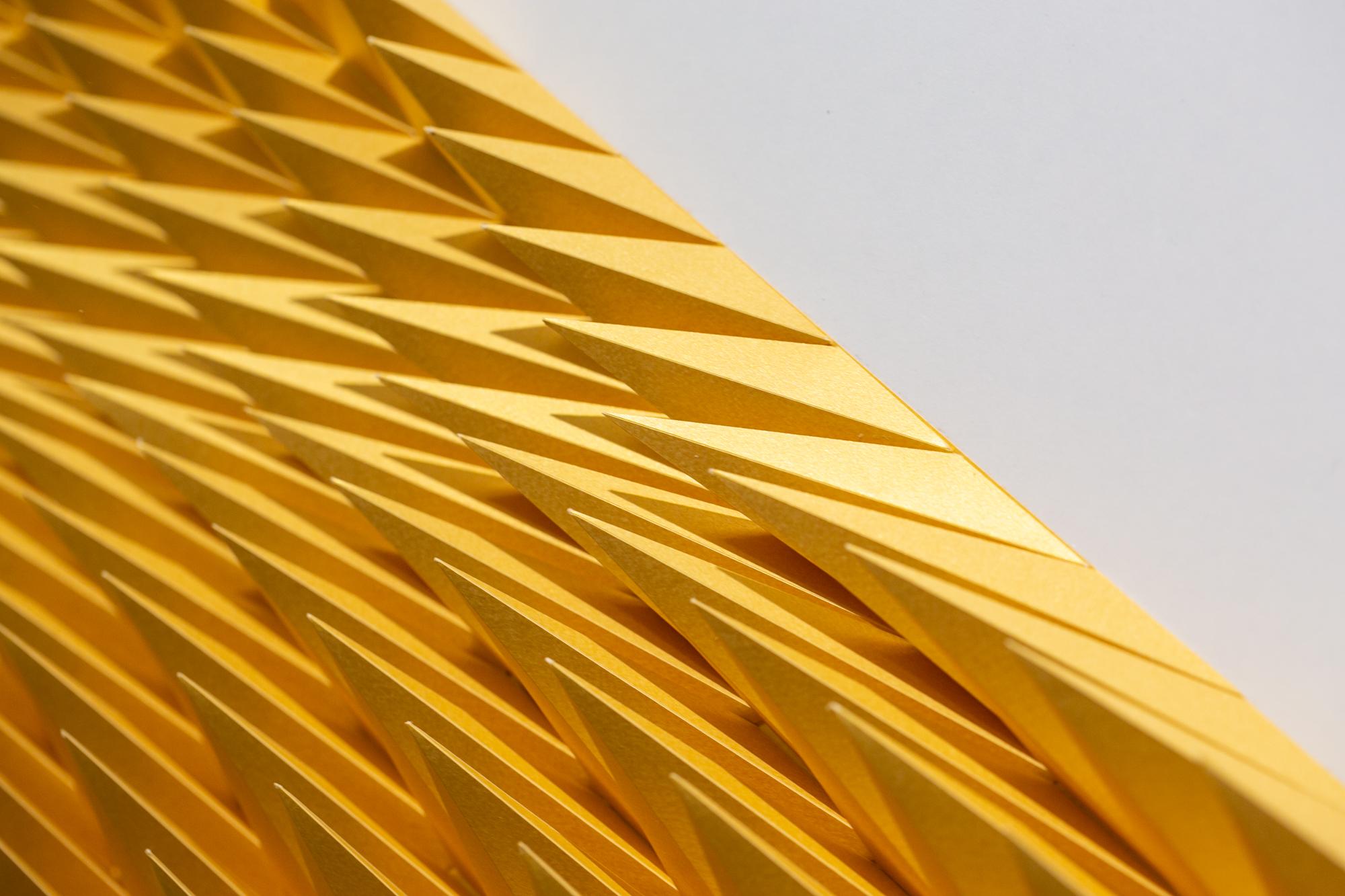 This gold orange wall-hanging sculpture titled 