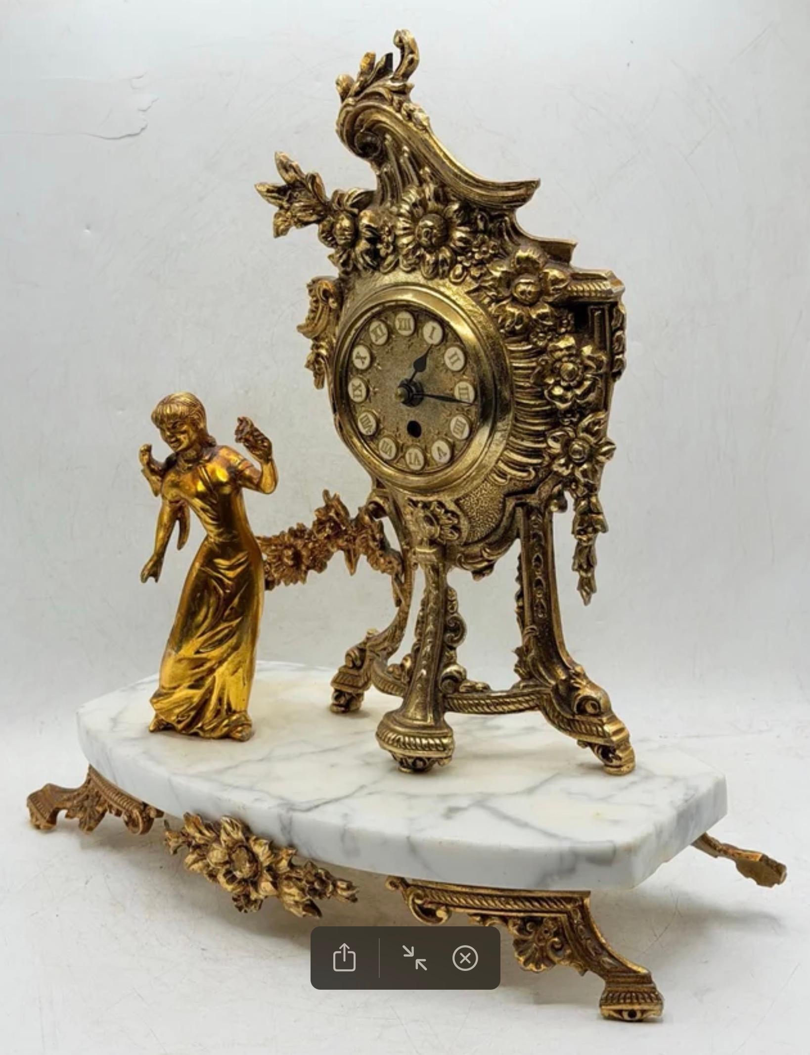 Elegante orologio da camino con base in marmo e dettagli in bronzo.

- Figura femminile in bronzo.

- Base in marmo venato.

- Cornice dell'orologio in bronzo ornata.

- Dimensioni: 40 x 35 x 16 cm