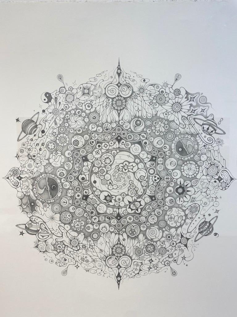 Patrones meticulosamente intrincados y pequeños planetas anillados rodean los bordes y se extienden hacia el exterior desde el centro de este mandala circular. Las viñetas con paisajes diminutos y horizontes infinitos continúan con los temas del